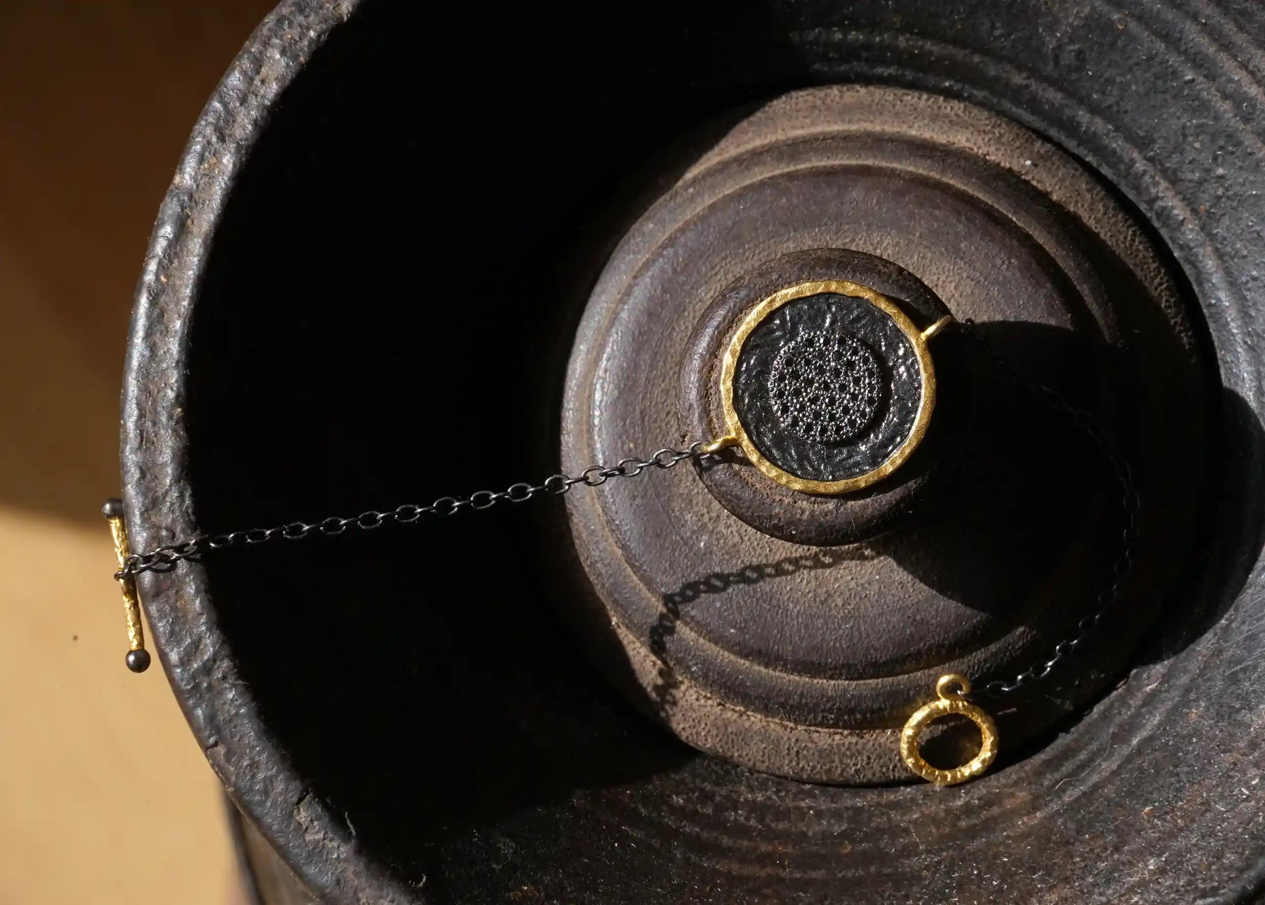 Brass bracelet from the Nuit des Temps collection with T-shaped clasp, featuring a medallion surrounded by a gold frame.