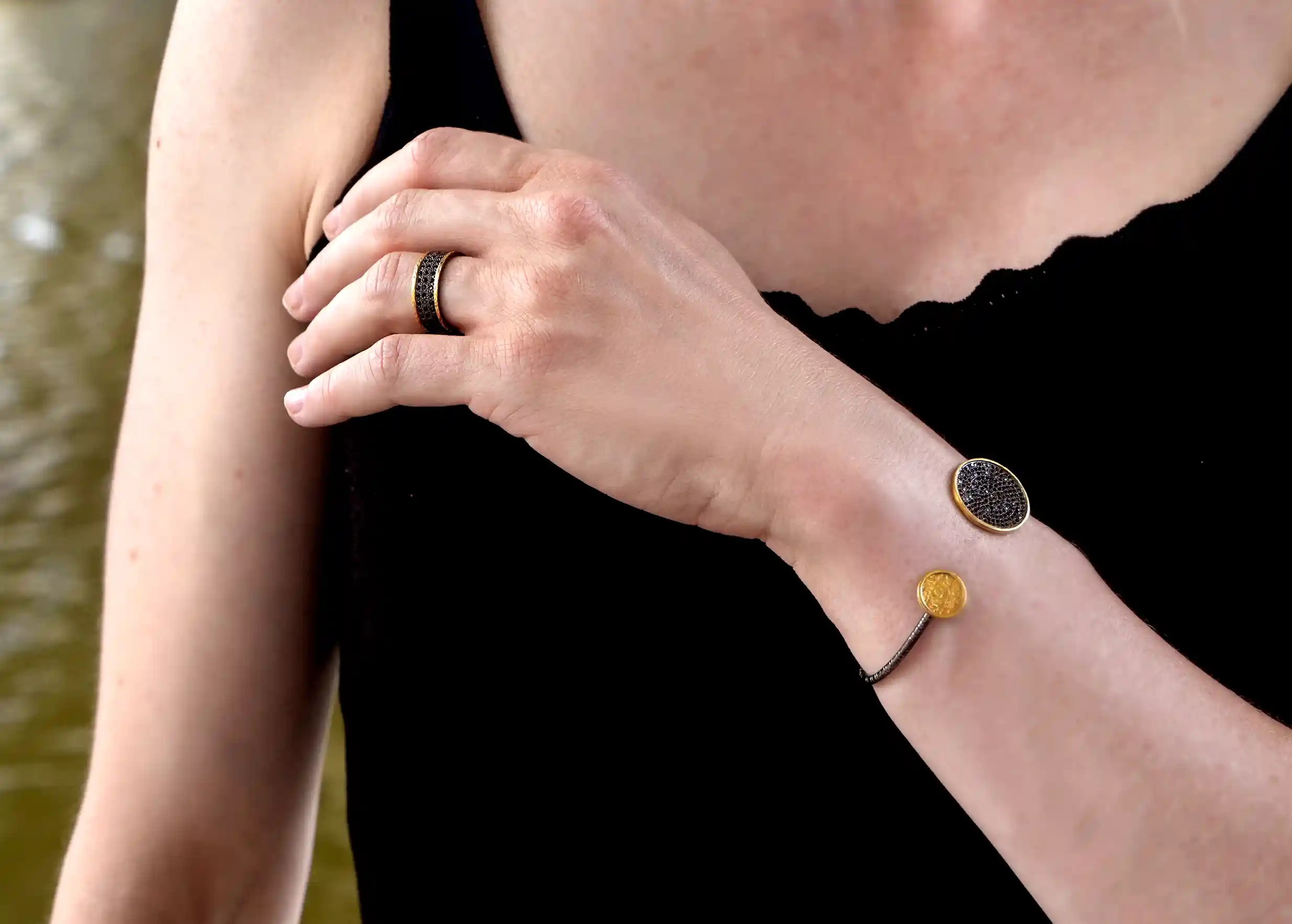 Handcrafted brass and zirconium bangle bracelet from the Dawn of Time collection worn around the wrist outdoors