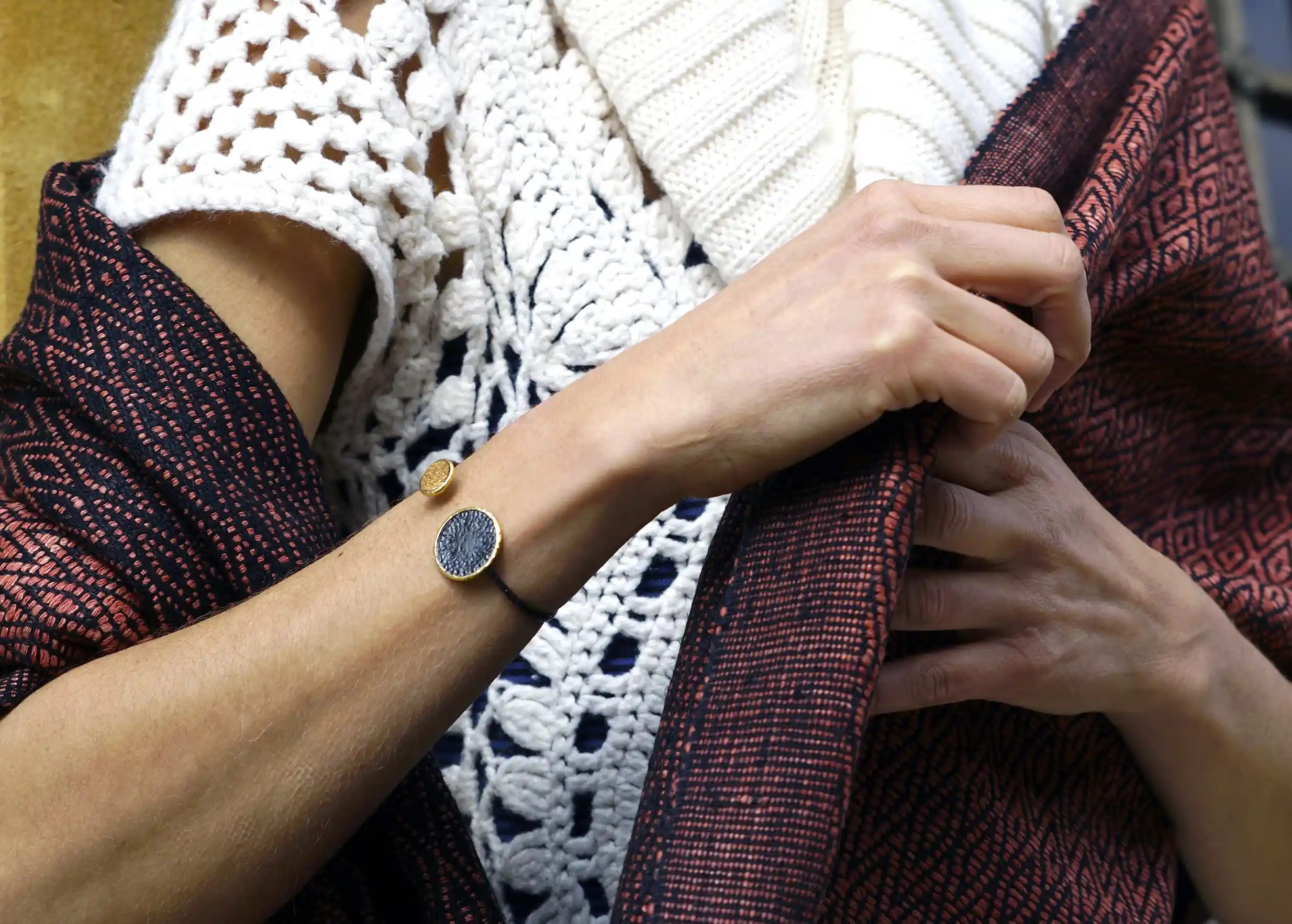 Bangle bracelet from the Dawn of Time collection in brass and zirconium, handcrafted, worn around the wrist outdoors.