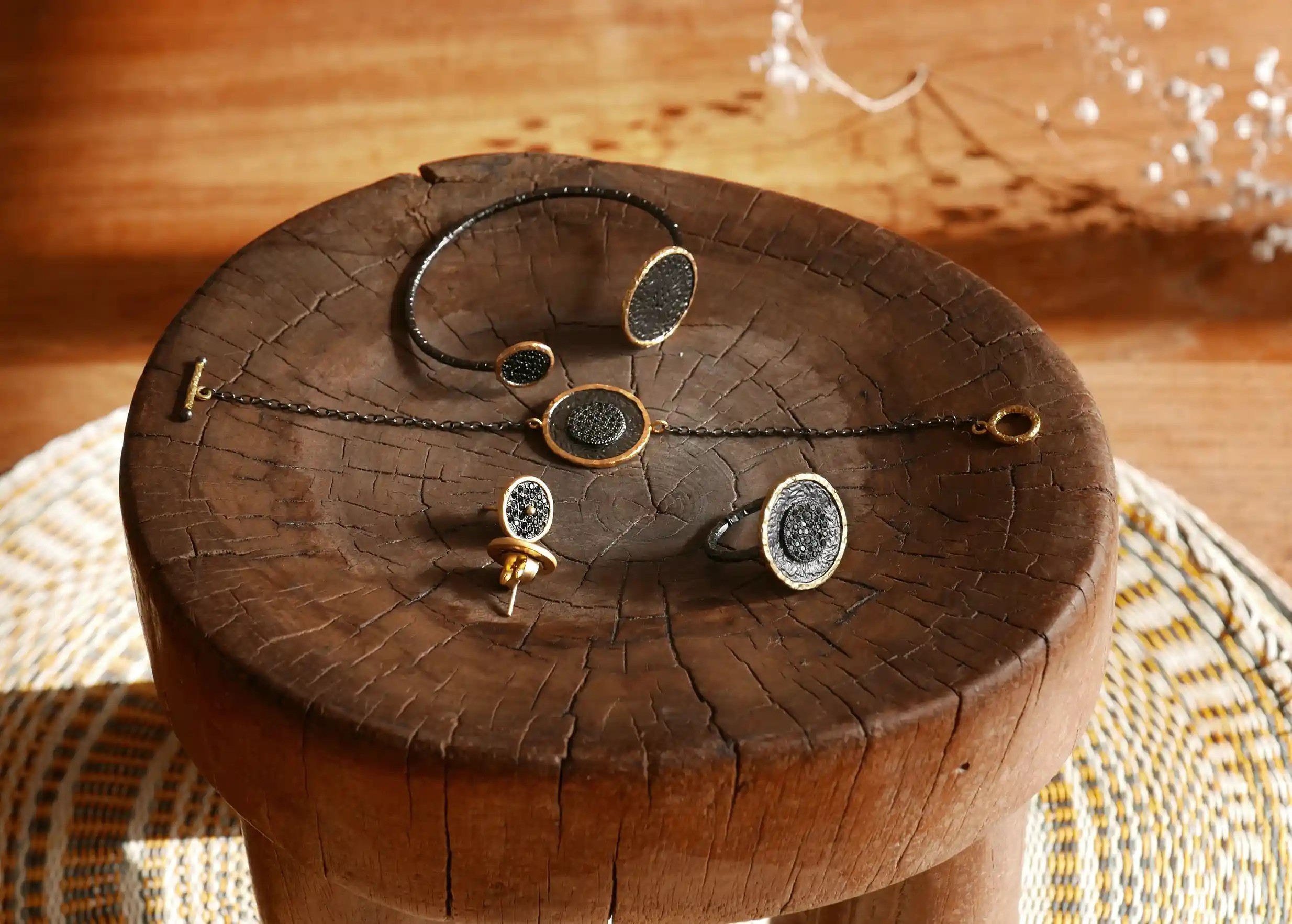 Collection de bijoux en laiton comprenant des bracelets, bagues et boucles d'oreilles, présentés sur un support en bois