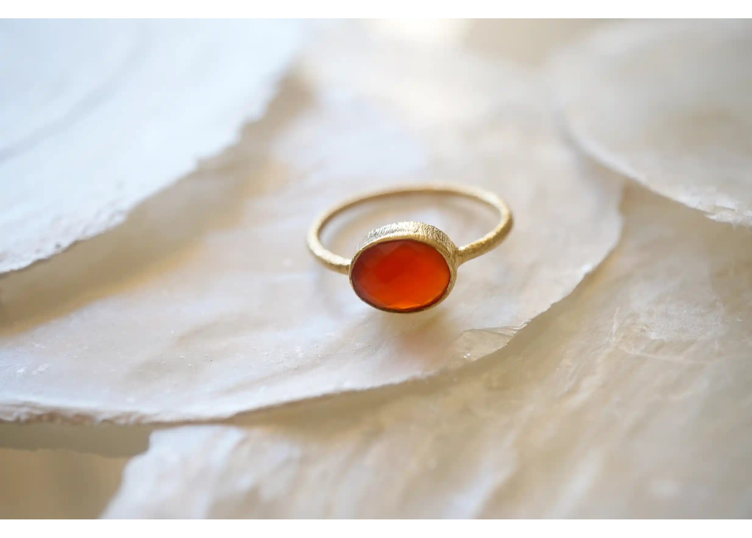 Gold and carnelian stone ‘Drop’ ring, displayed on a stone