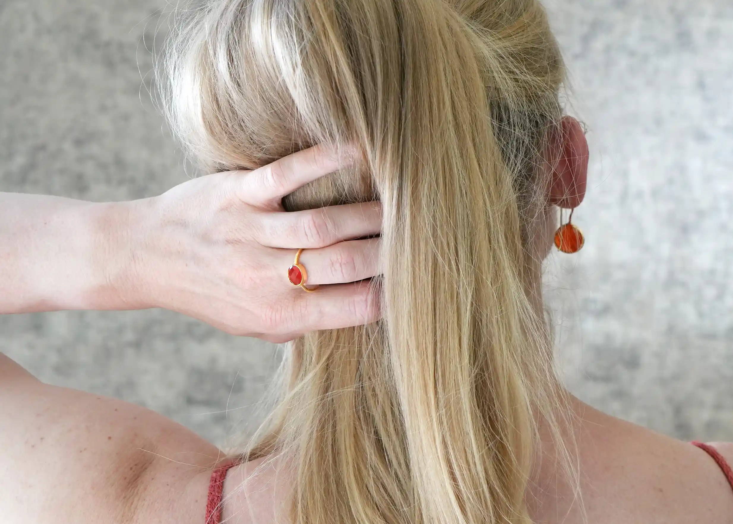 Woman from behind wearing a gold-plated Drop ring with carnelian stone