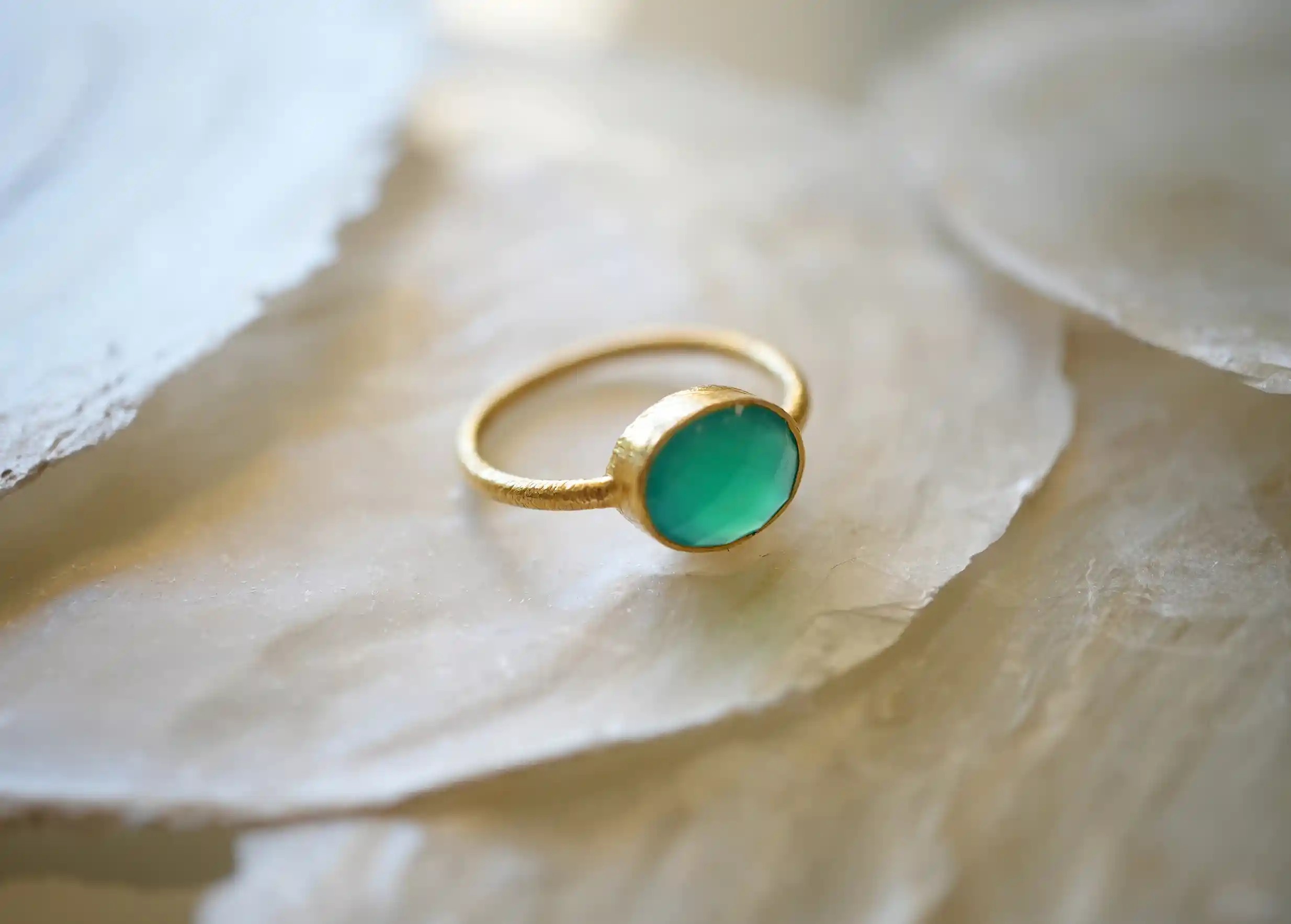 Zoom sur bague « Drop » Or & pierre vert onyx exposés sur une pierre