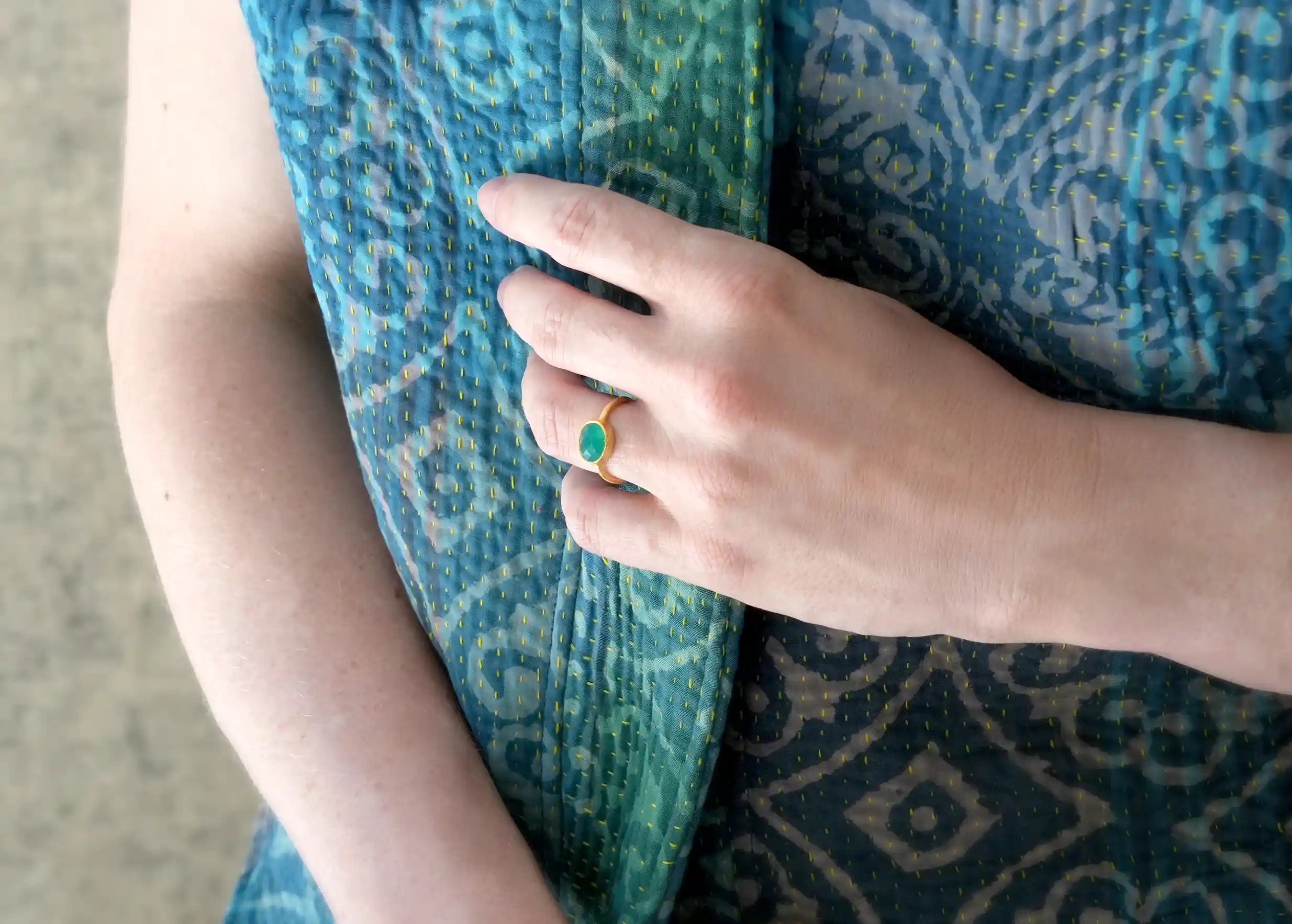 Zoom sur une bague « Drop » Or & pierre vert onyx porté par une femme en intérieur