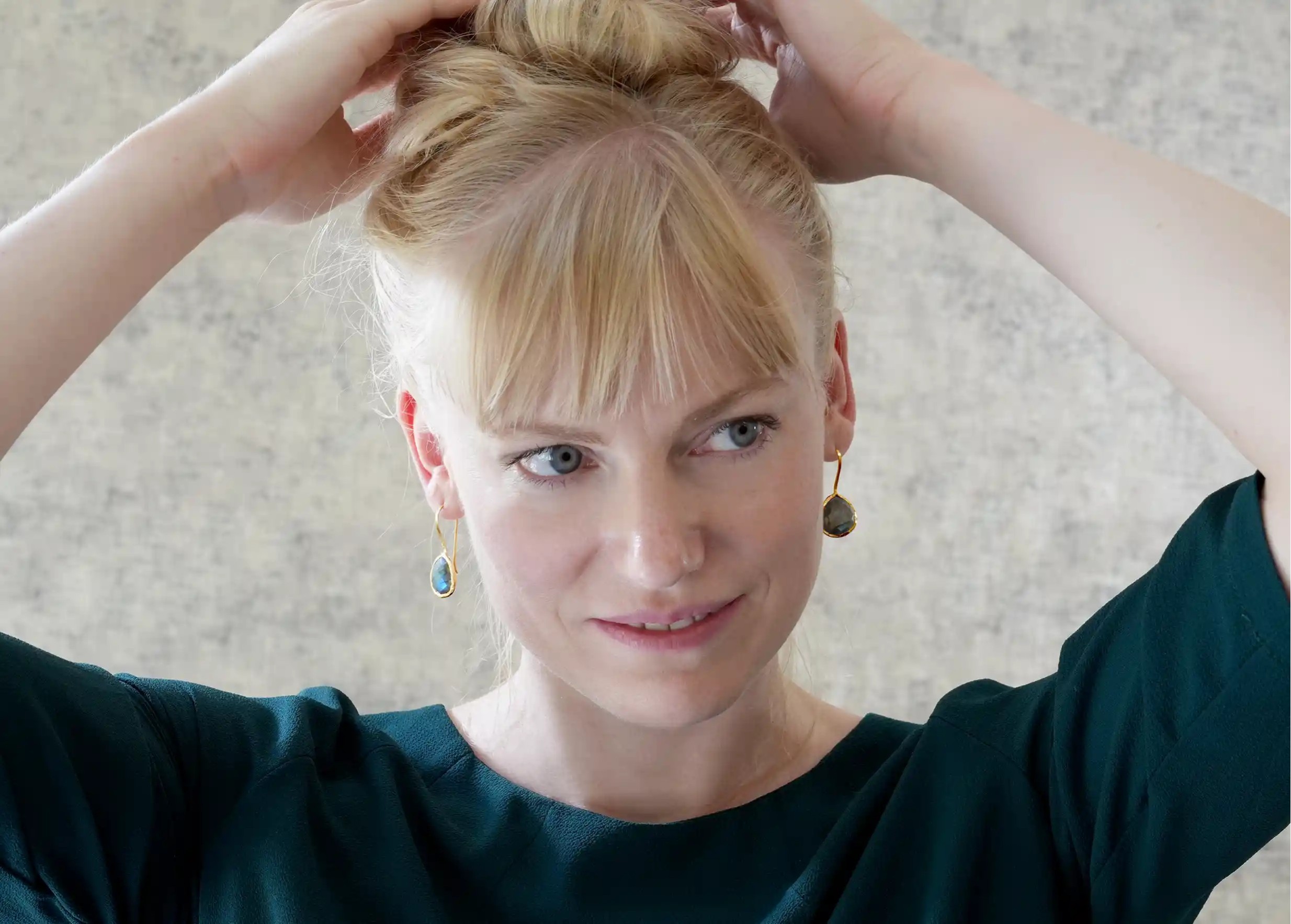 Woman wearing gold and labradorite drop earrings, Yamuna collection