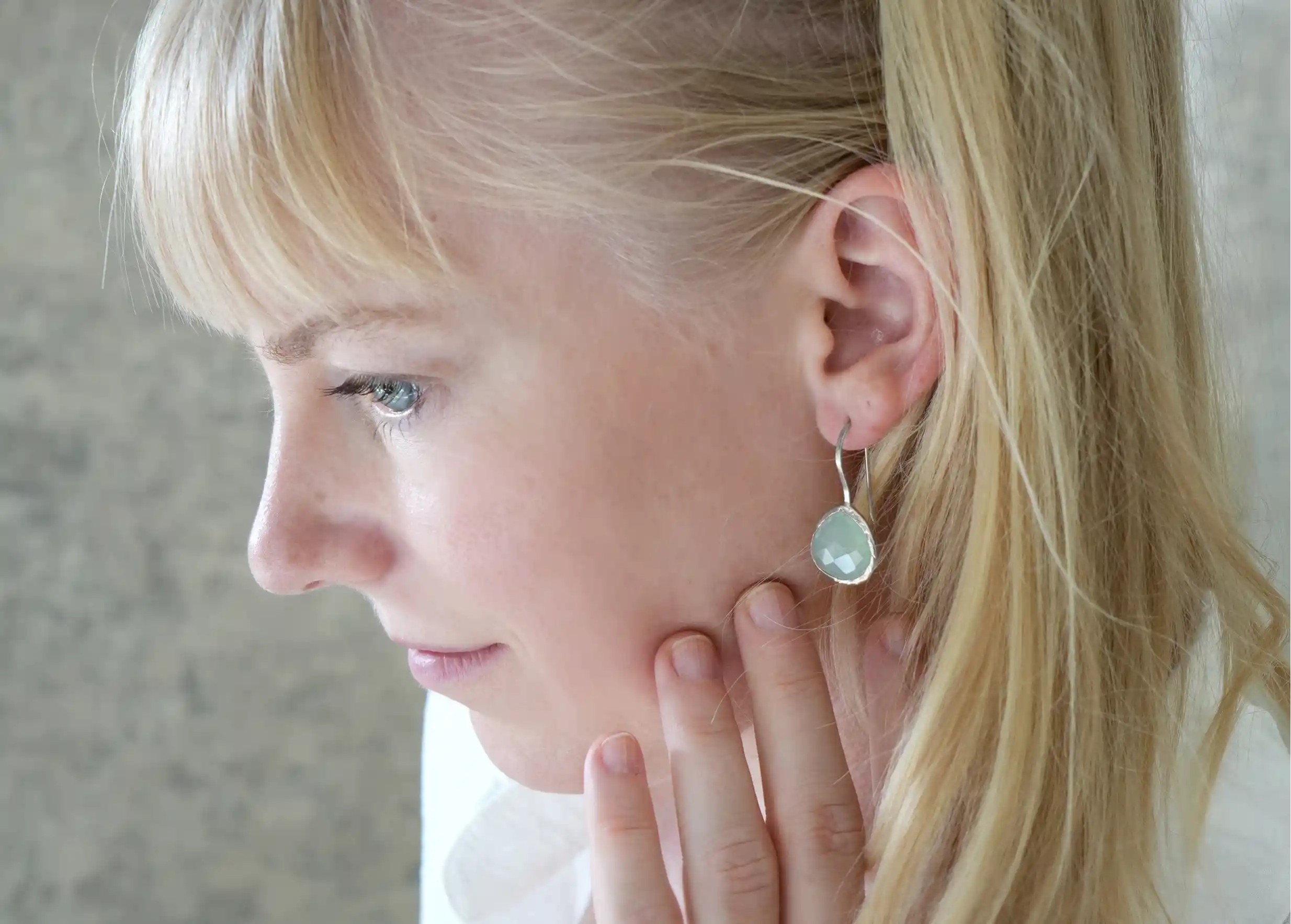 Femme de profil portant des boucles d’oreilles « Drop » argent & pierre calcedoine, collection Yamuna