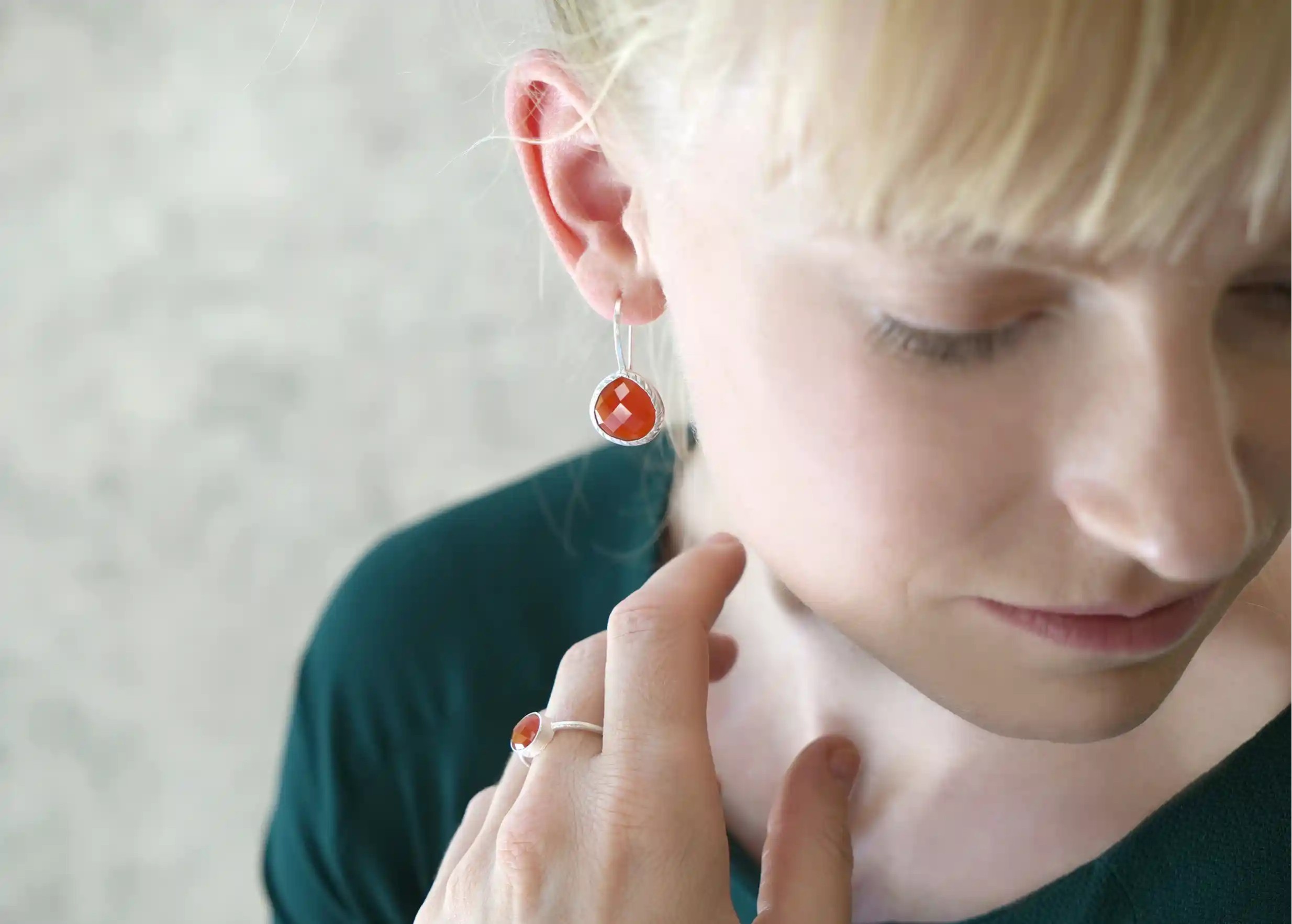 Woman wearing a silver and carnelian stone ‘Drop’ ring and earrings, Yamuna collection