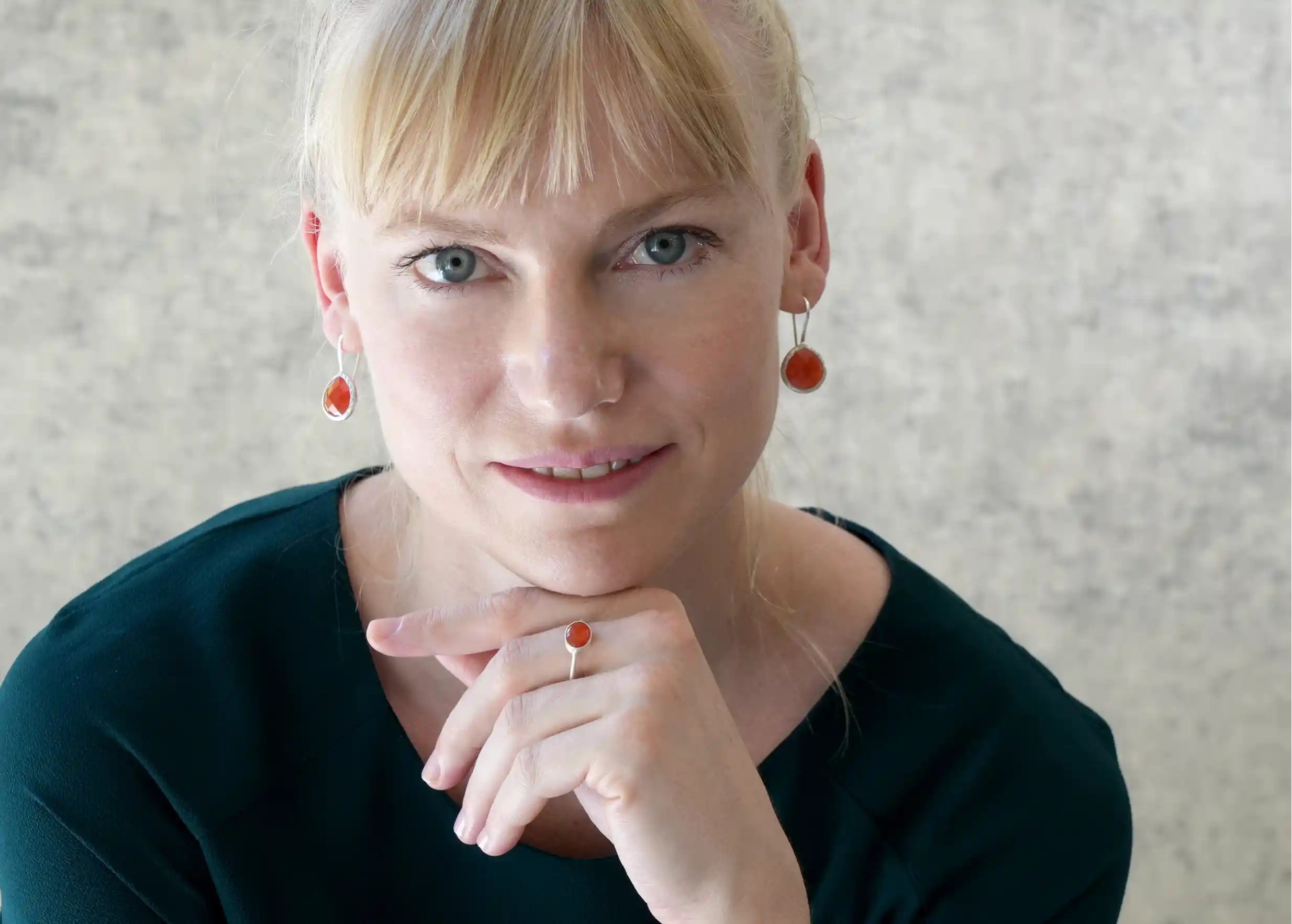 Woman wearing silver and carnelian stone ‘Drop’ ring and earrings, photo taken indoors