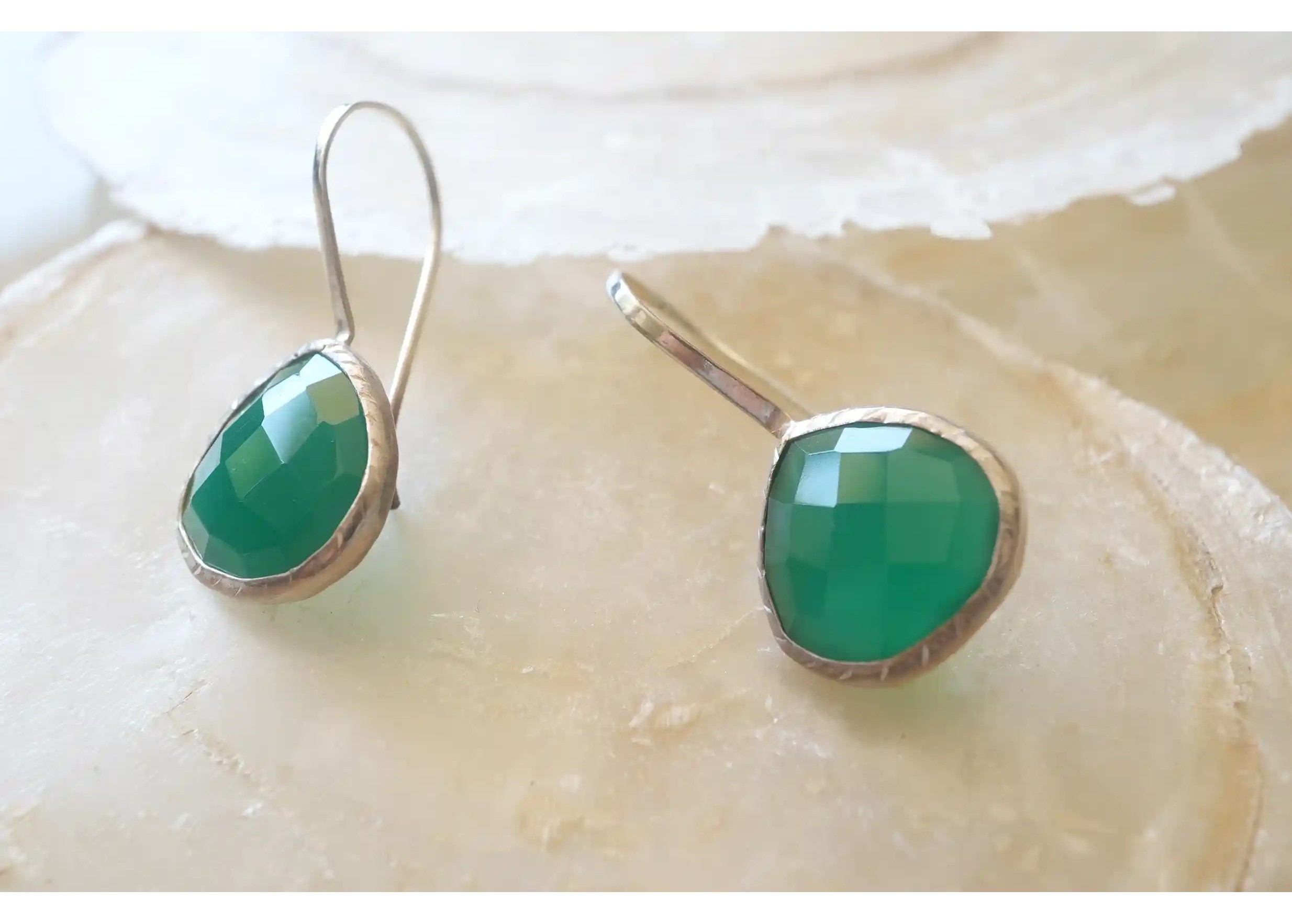 Silver and green onyx drop earrings, displayed on the floor