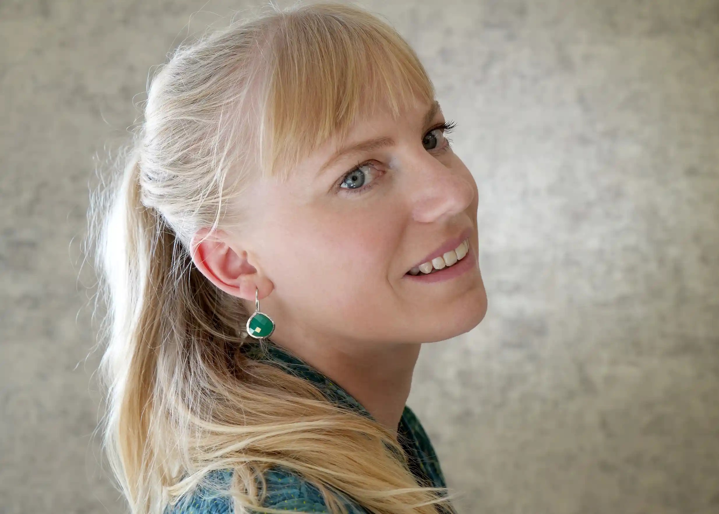 Femme de profil portant des boucles d’oreilles « Drop » argent & pierre onyx vert, collection Yamuna