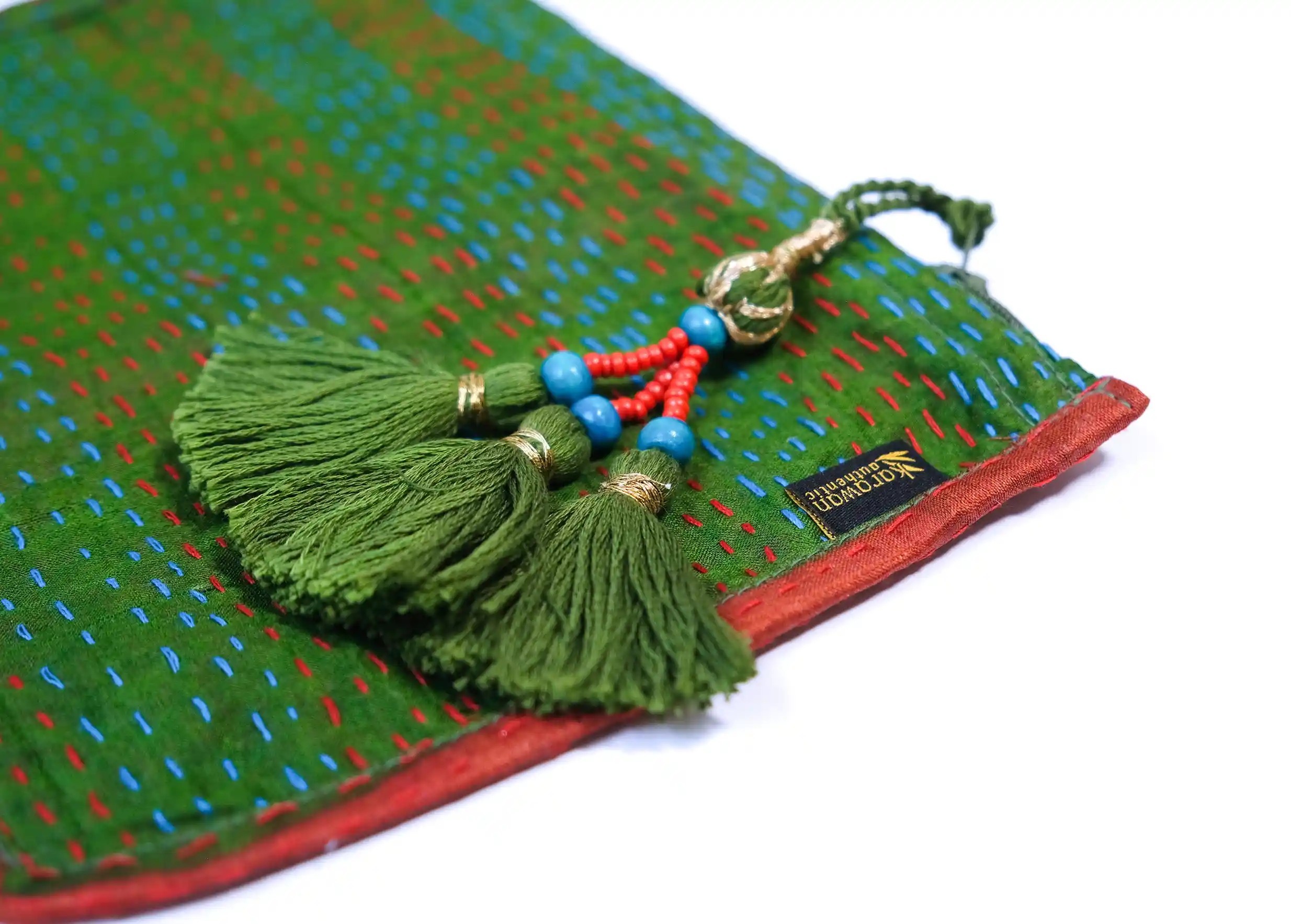 Close-up of the patterns and pompom on the handmade recycled kanta silk clutch bag, model no. 10, with pompom