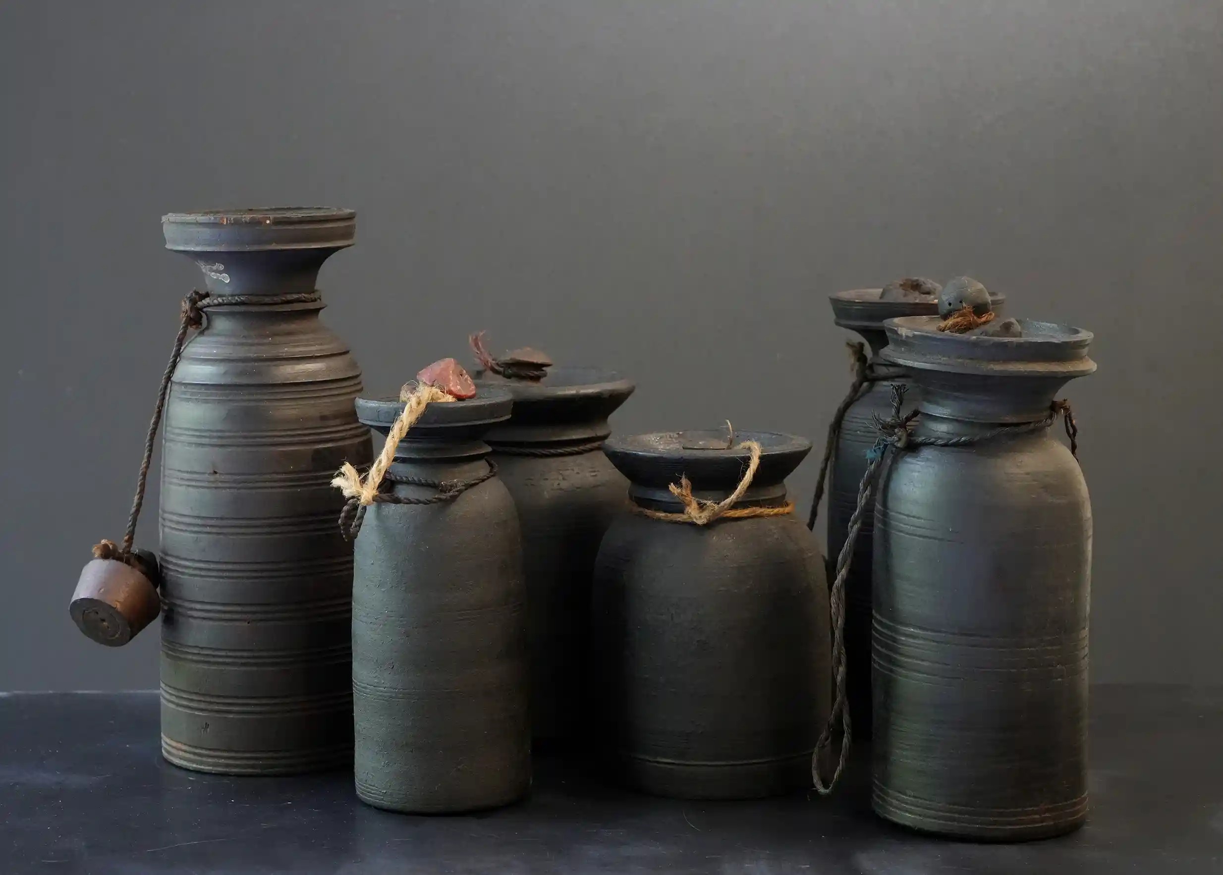 Six wooden pots containing Himalayan yak butter, photo taken against a dark background