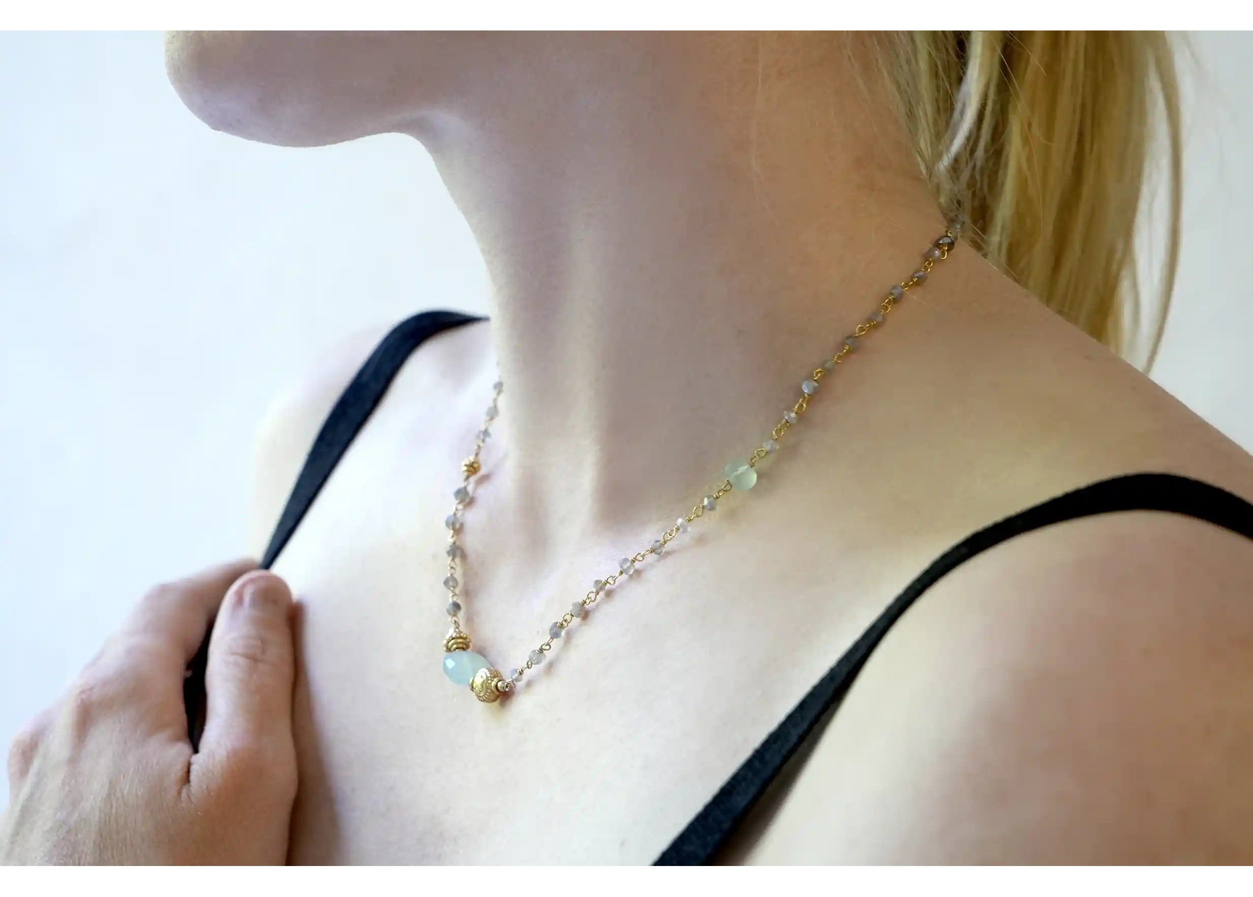 ‘Ani’ gold-plated necklace with aqua chalcy and labradorite stones, worn by a woman