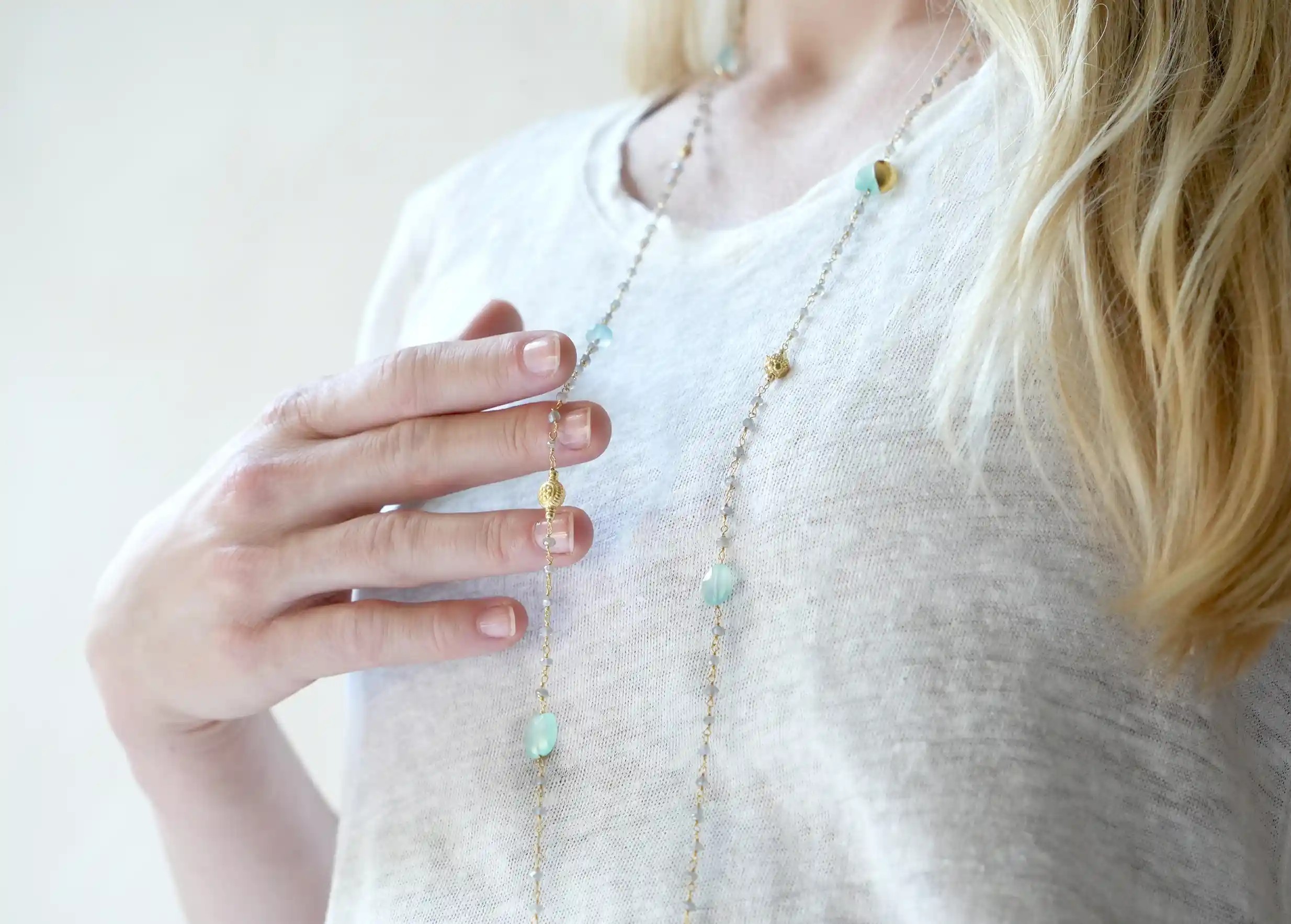 Sautoir « Ani » Or & pierres de calcédoine et labradorite, enroullé autour des doigts d'une femme