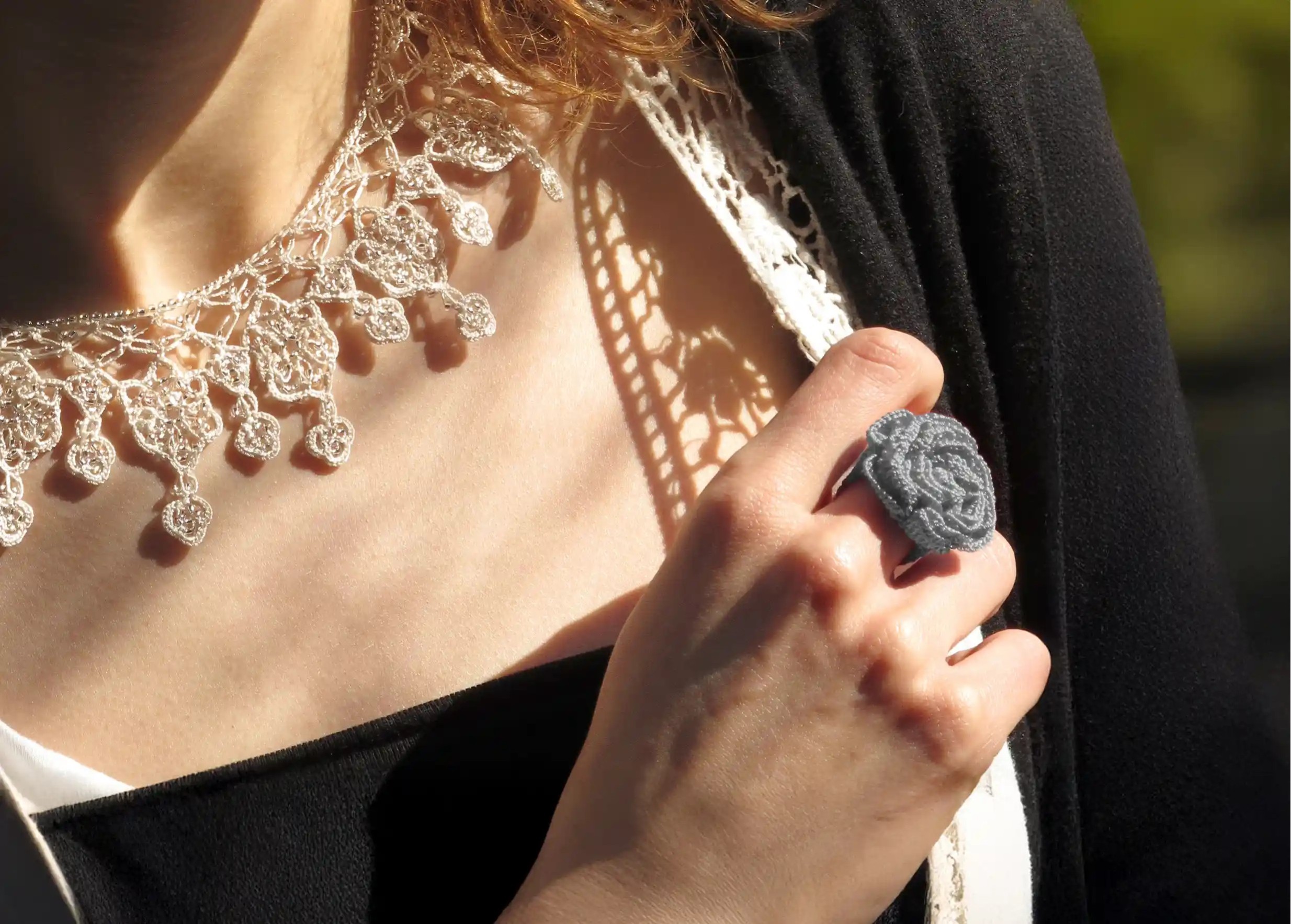 Woman outdoors wearing a Beklis lace ring in cloud grey with a twisted floral design