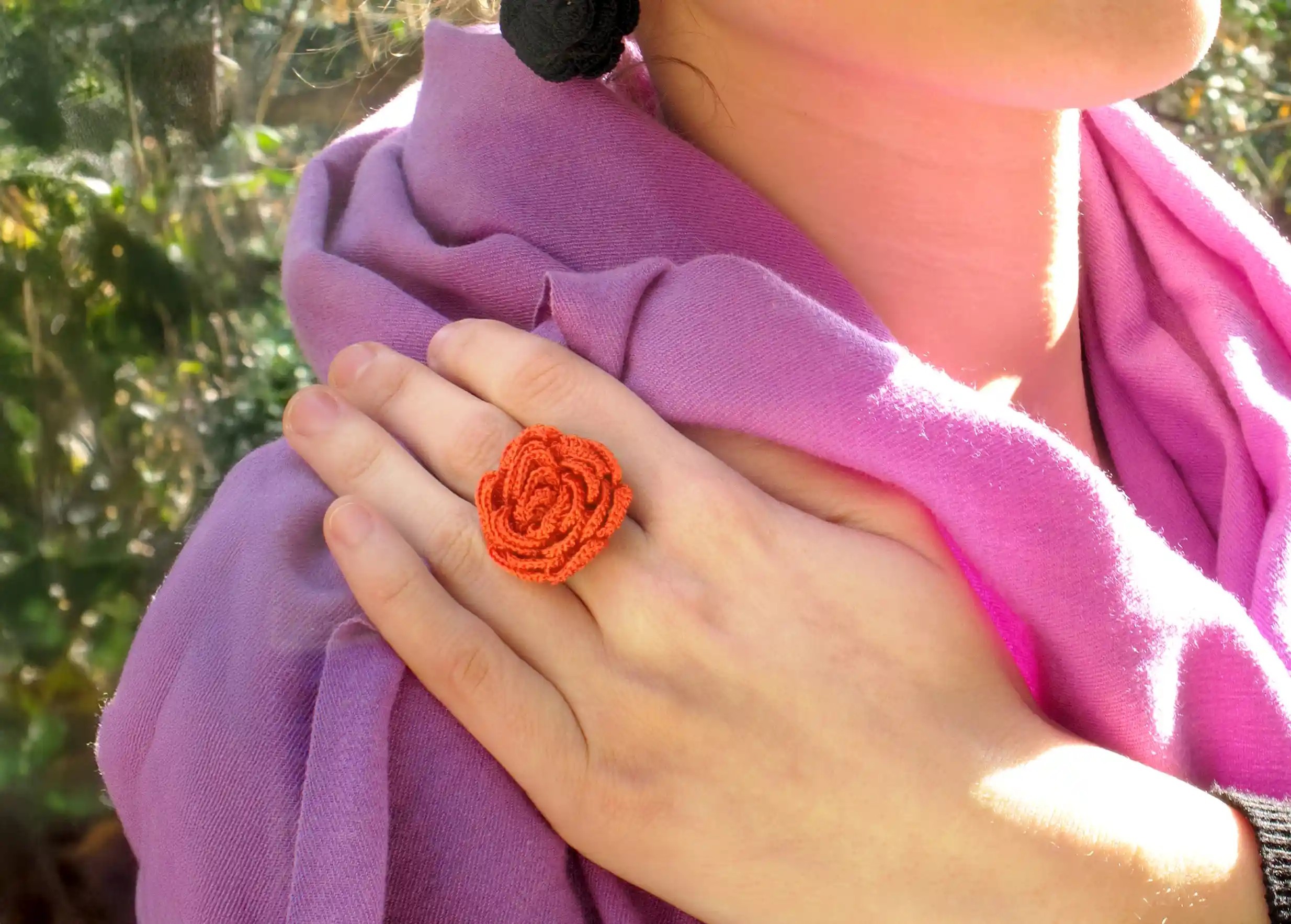 Femme portant une bague en dentelle Beklis couleur papaye au design floral torsadé