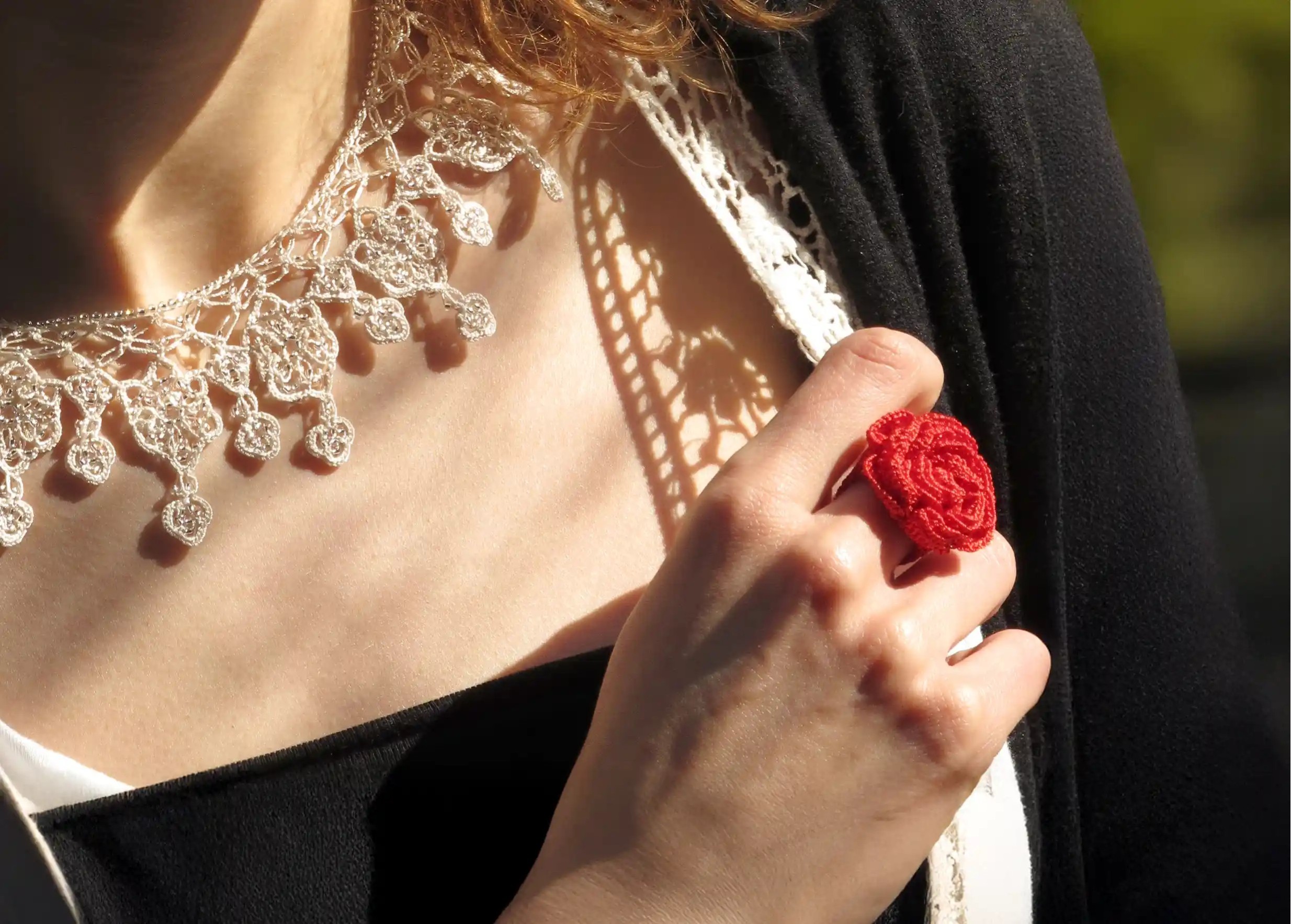 Woman wearing a red Belkis ring and an Oya lace necklace by Karawan