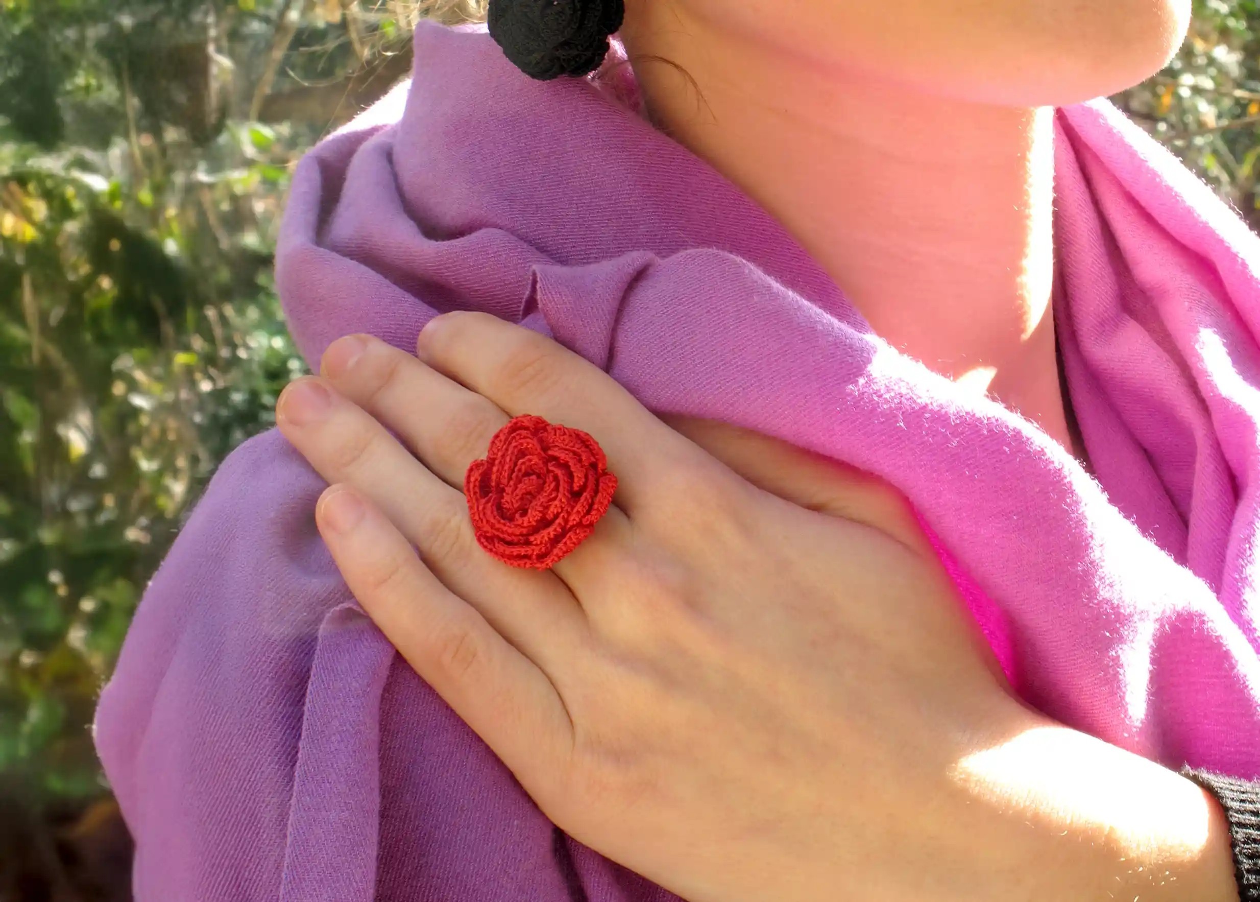 Red colored Oya lace ring worn by a woman outdoors