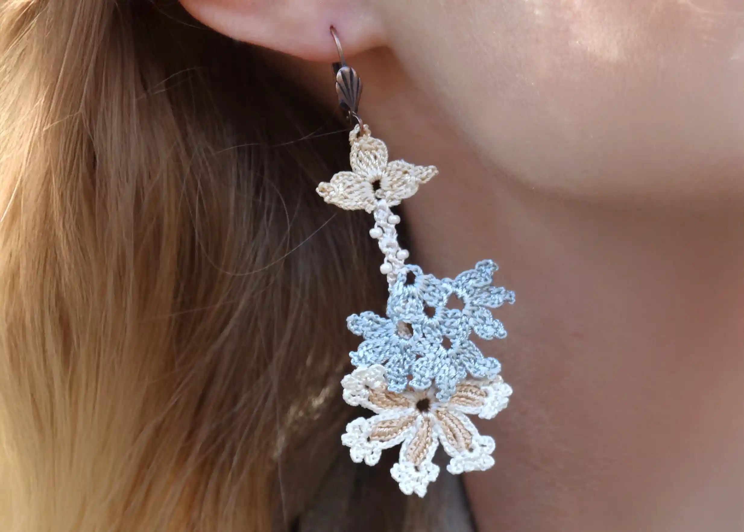 Zoom sur boucles d'oreilles en dentelle Kapadokya, modèle double winter portées par une femme