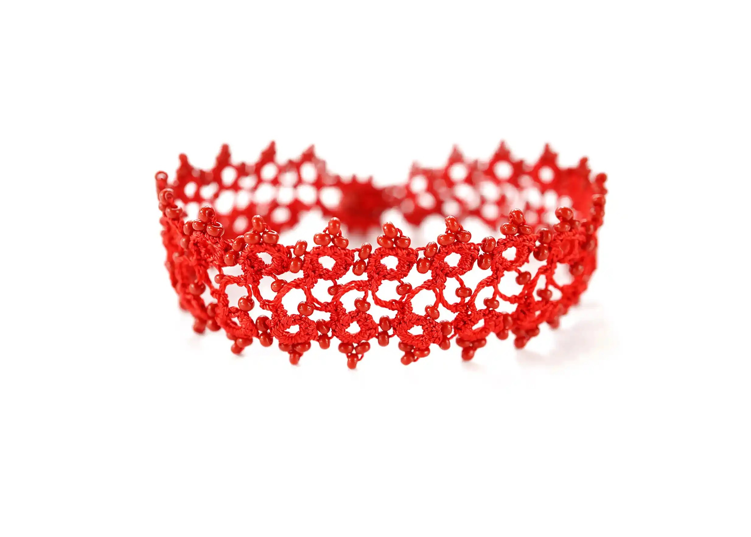 Bracelet en dentelle Husnu de couleur rouge avec des perles, posé sur fond blanc