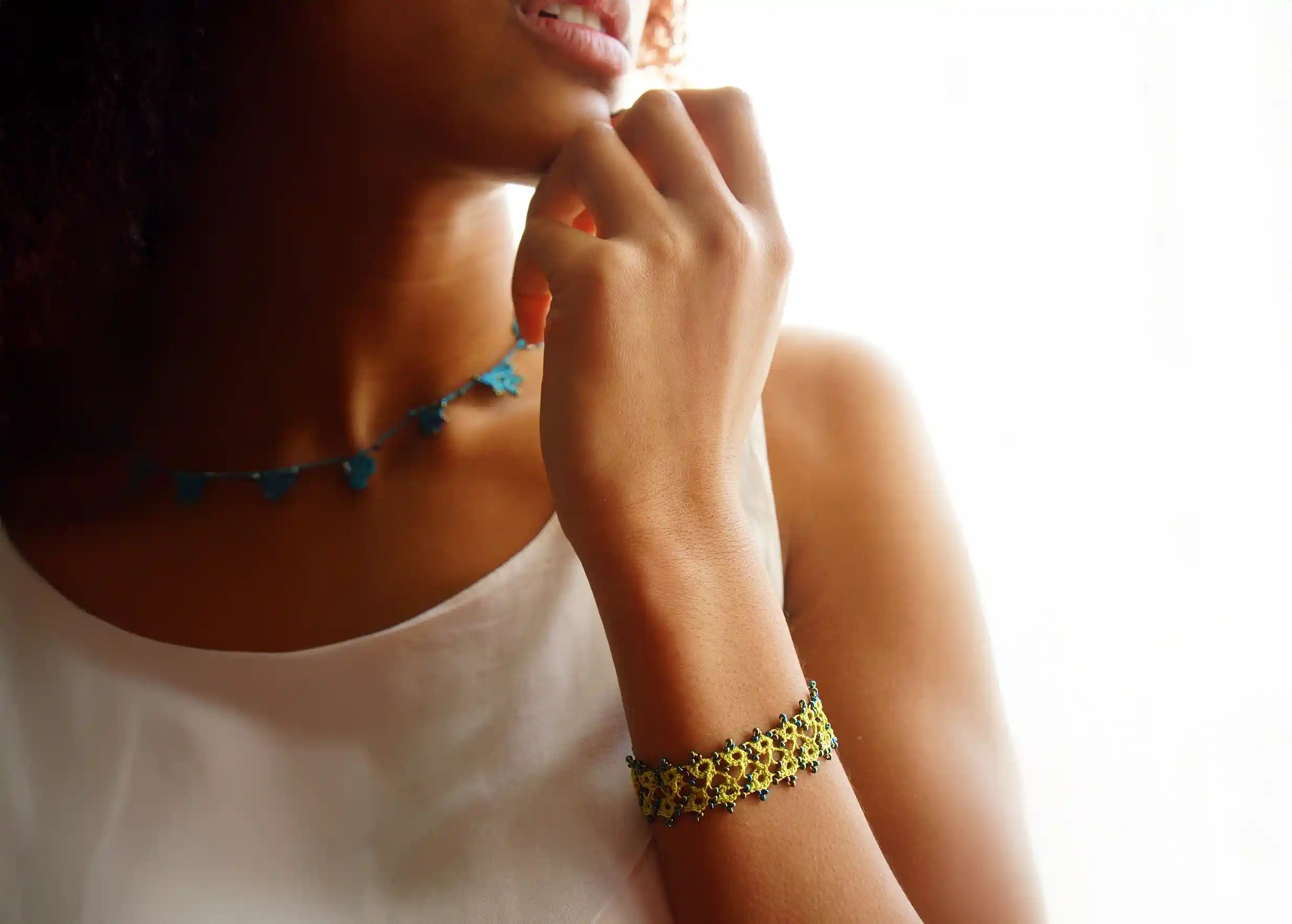 Bracelet en dentelle Husnu couleur Vert lichen porté au poignet par une femme dans un cadre lumineux