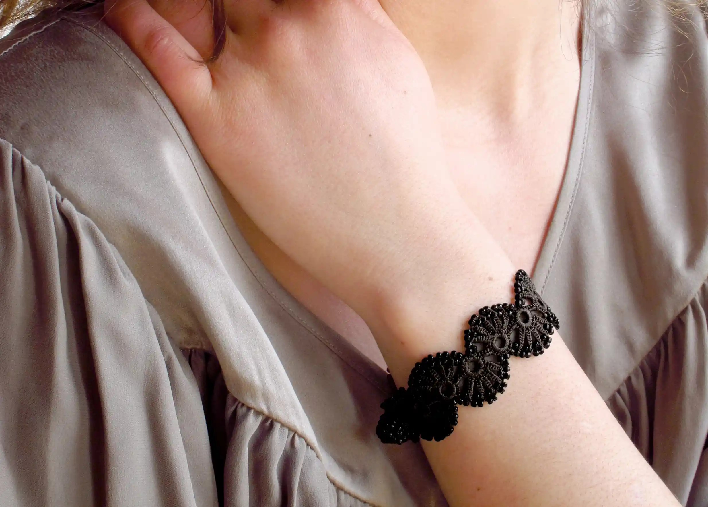Bracelet en dentelle noir carbone de couleur noir carbone porté par une femme en extérieur