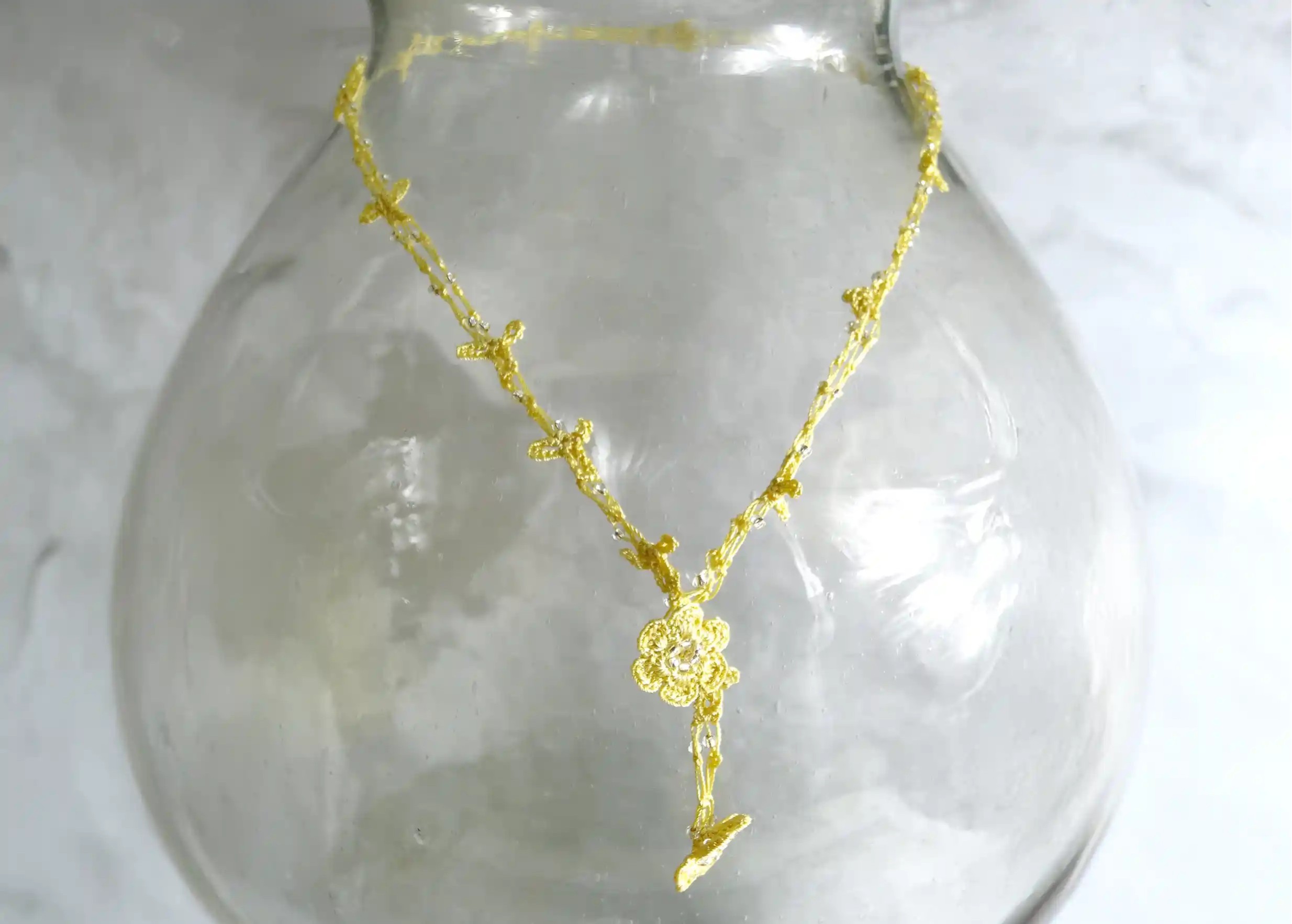 Chainette en dentelle Oya, coloris vanille suspendu sur un vase