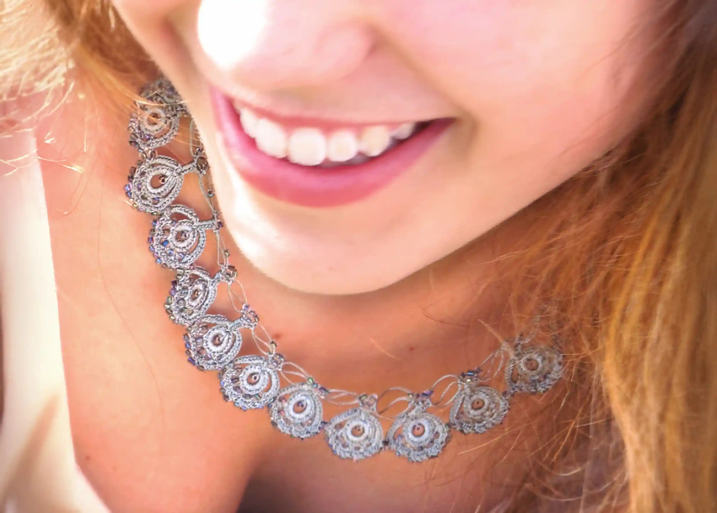 Eda lace necklace in pearl grey, worn around a woman's neck
