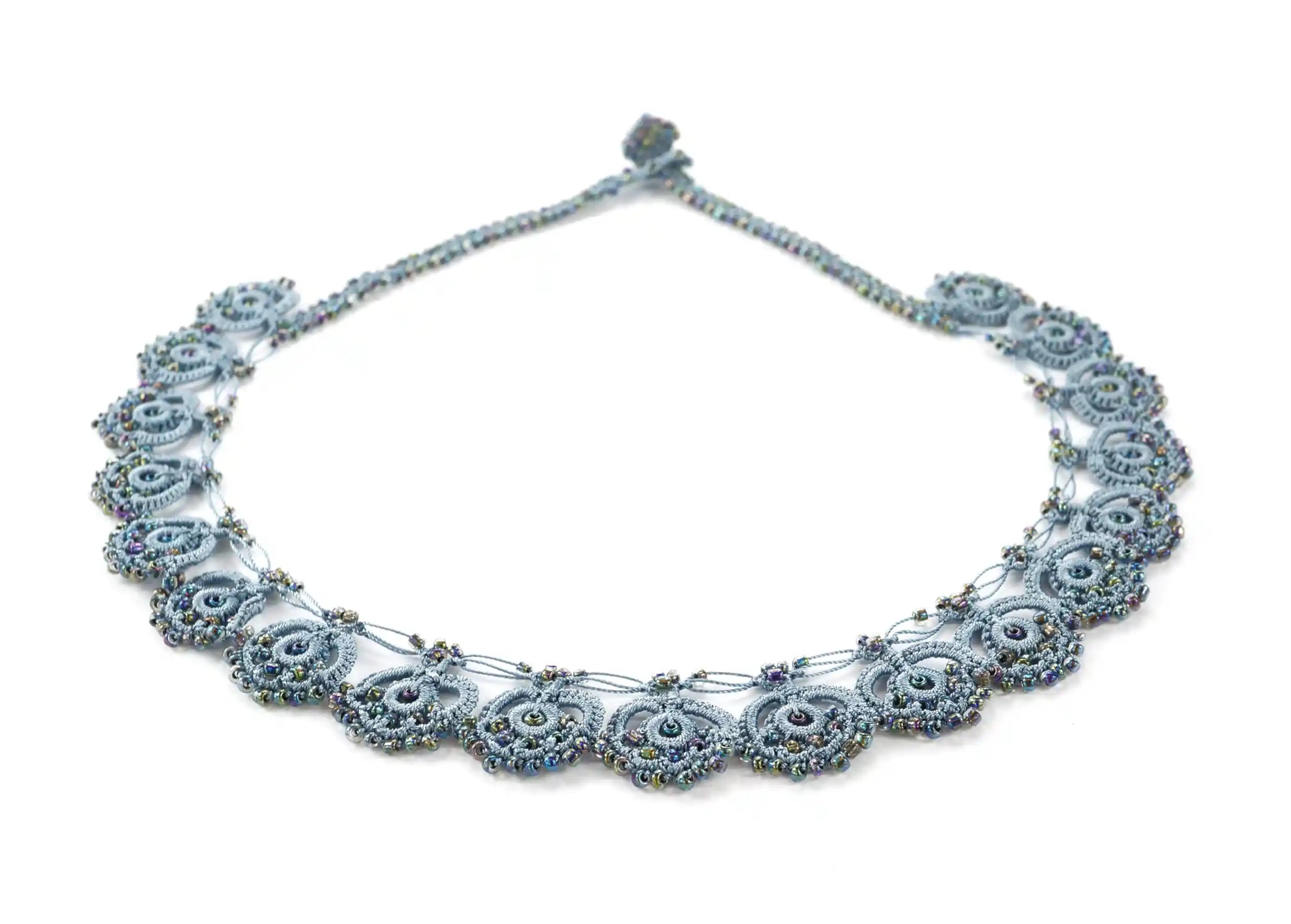Collier en dentelle Eda de couleur grise, orné de perles, posé à plat sur fond blanc