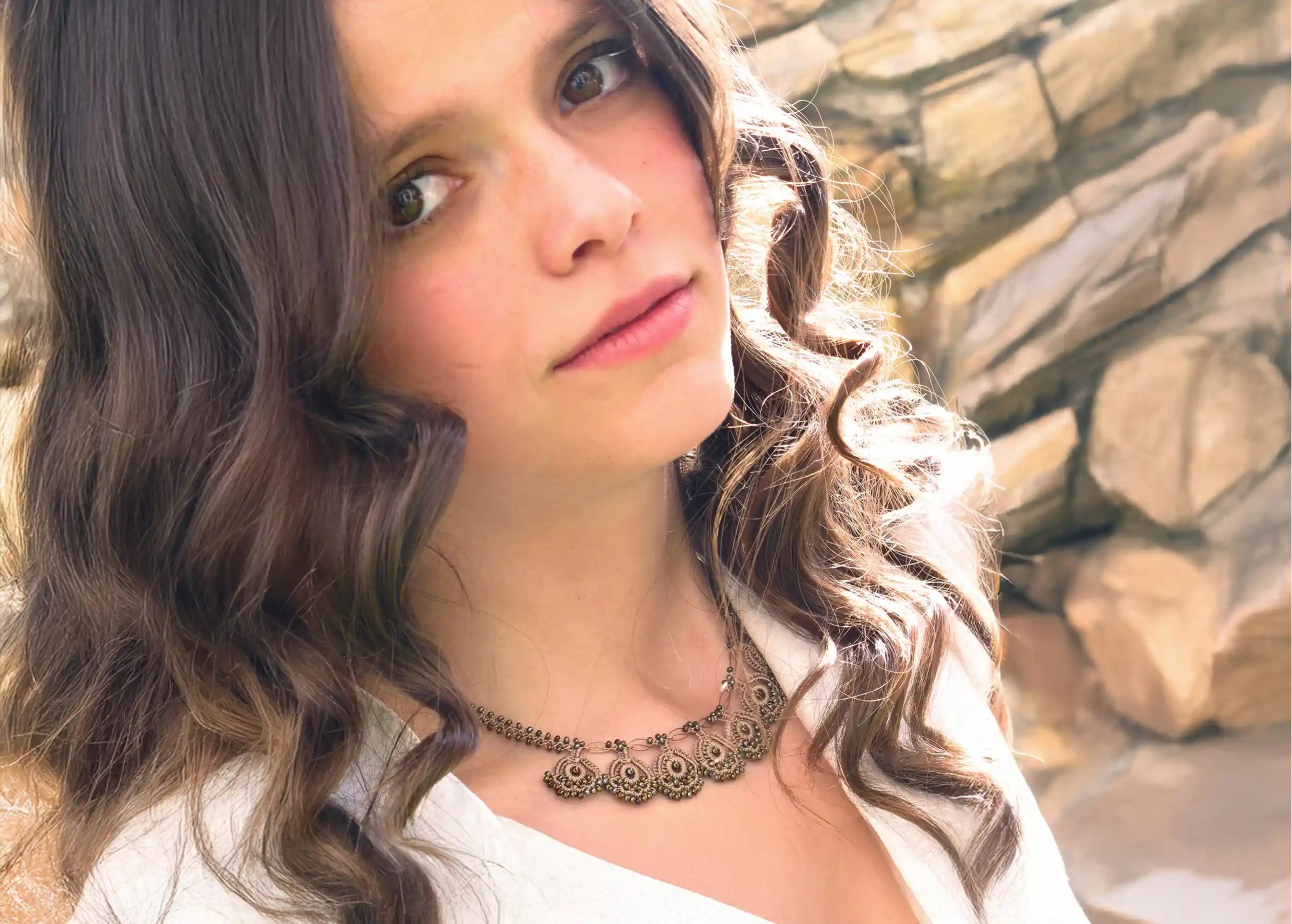 Eda lace necklace in golden sand colour, worn around the neck and touched by hair