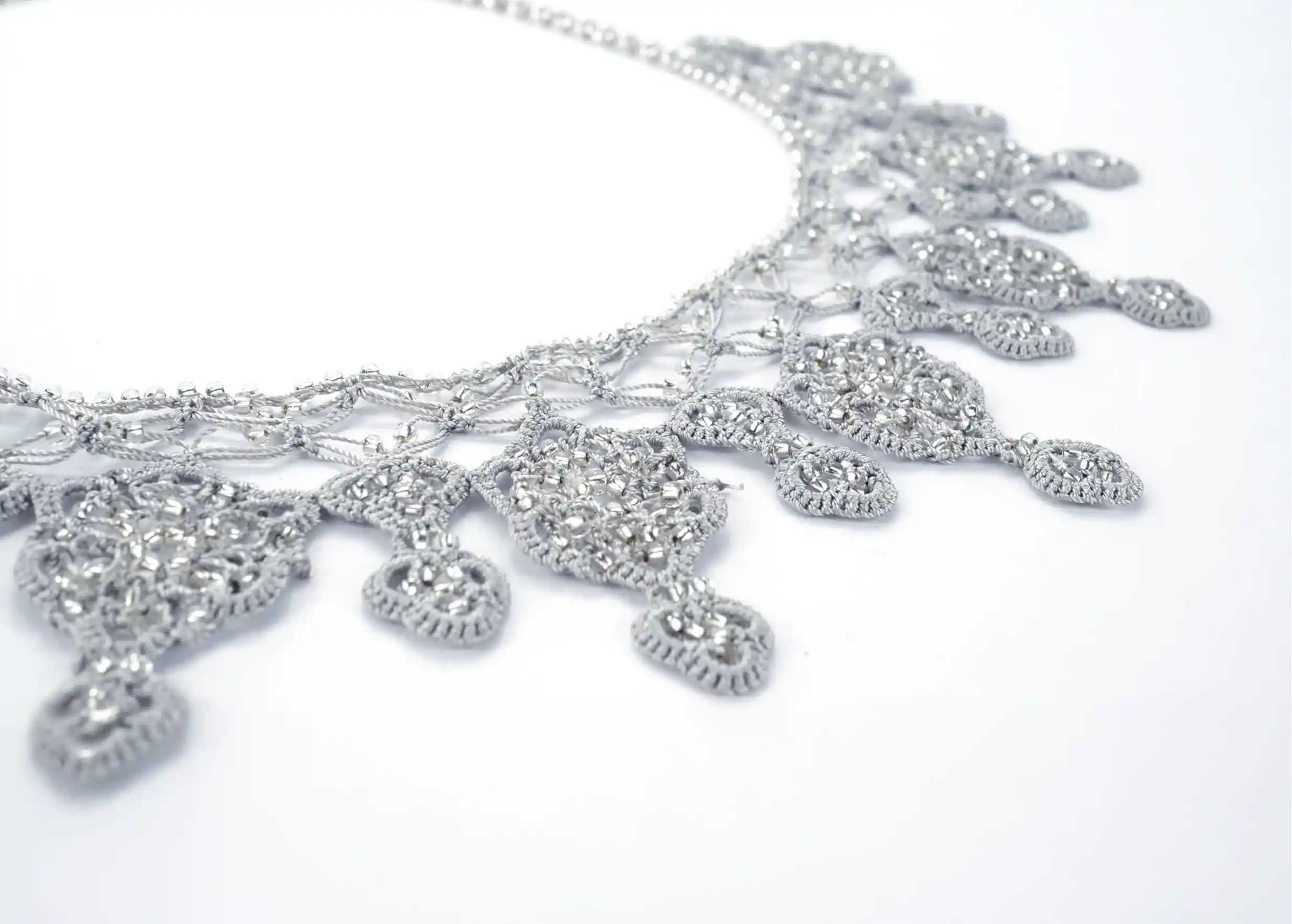 Focus on the motifs of the Sonya cloud grey necklace, hand-woven in lace