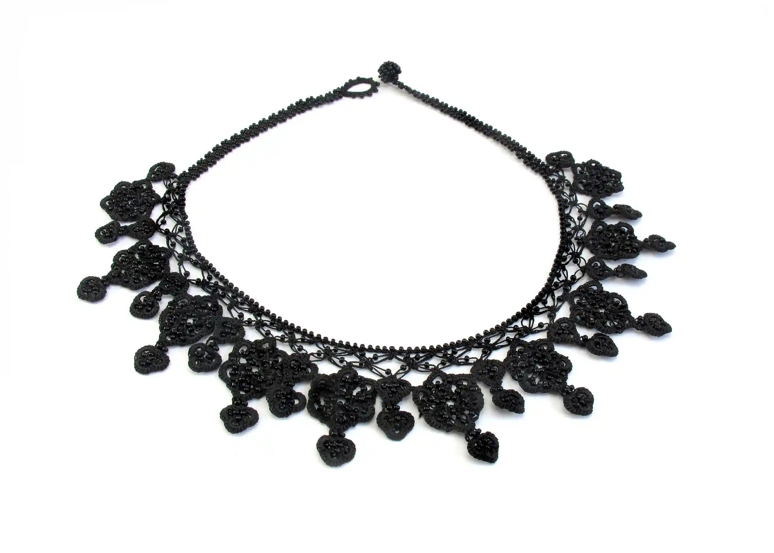 Collier en dentelle Sonya par Karawan, au coloris noir carbone, posé à plat sur fond blanc