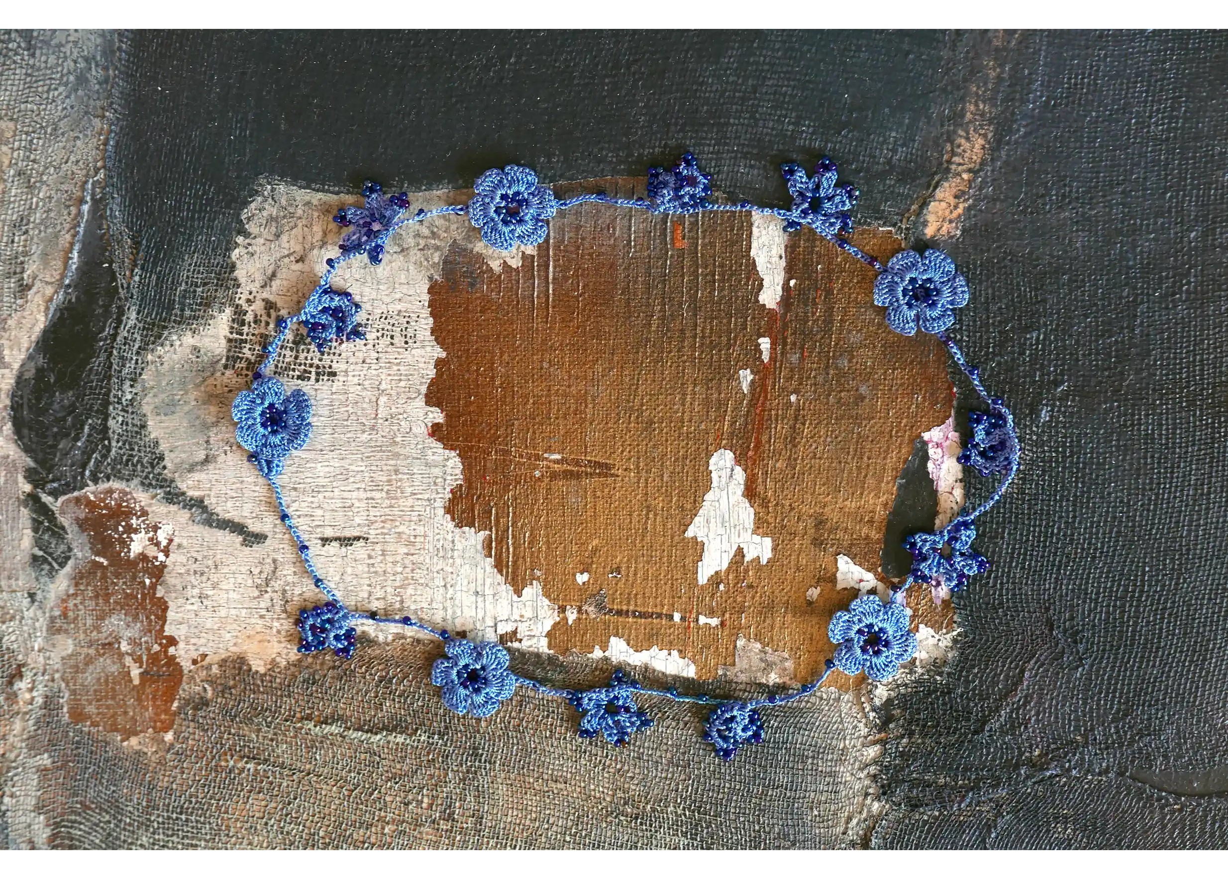 Indigo-coloured Crystal lace choker with floral motifs and pearls on a textured background