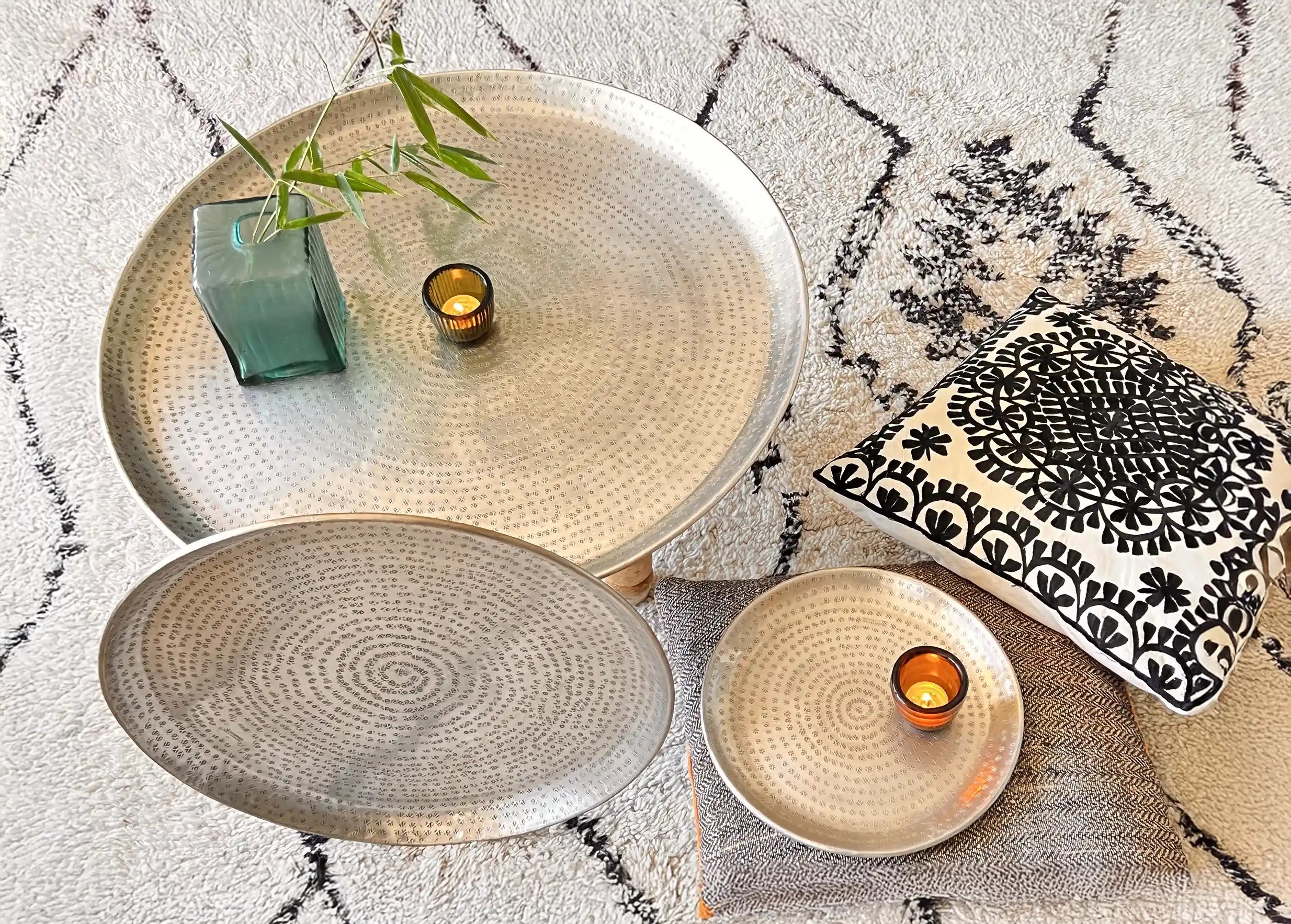 Brass trays from the Shams collection displayed on the floor on a rug