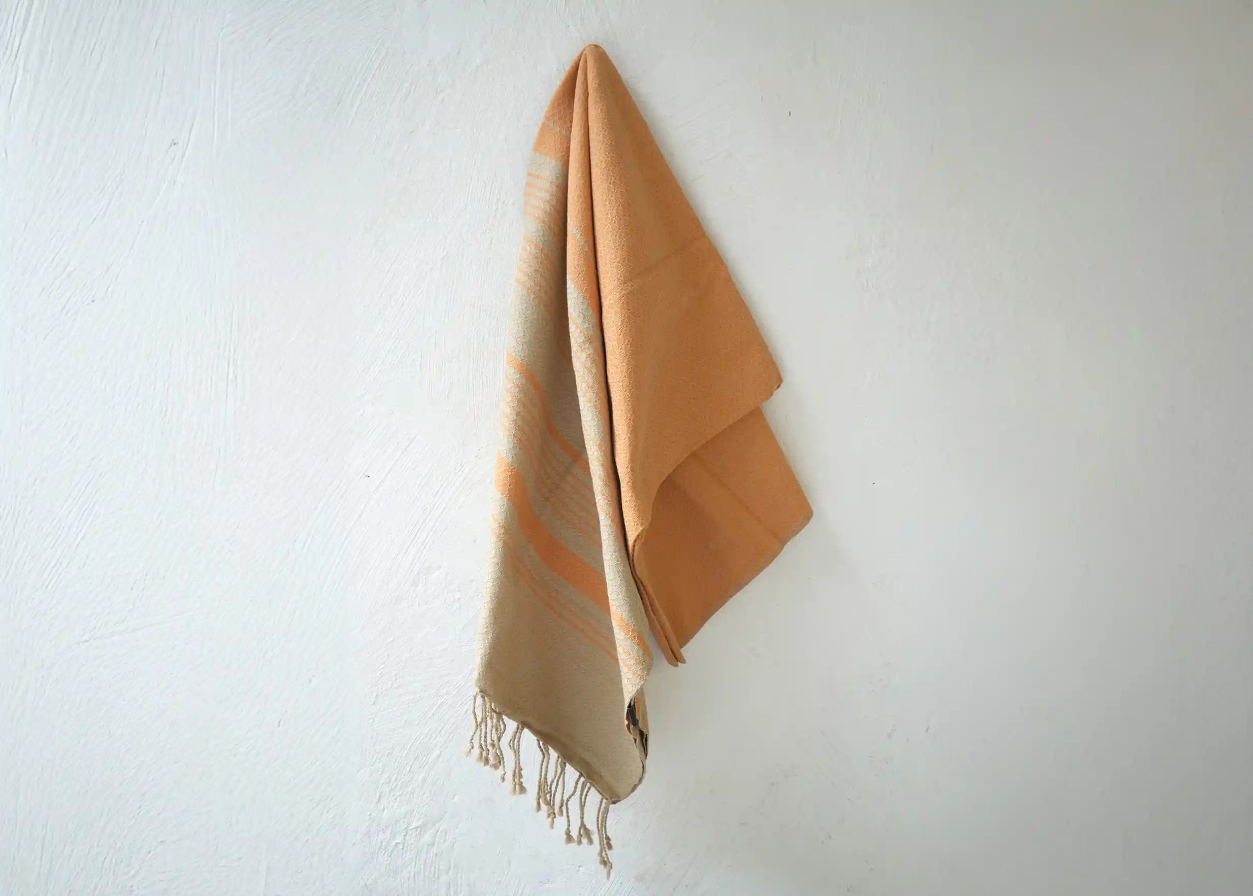 Fouta de la marque Karawan authentic en coton bio, suspendue contre un mur
