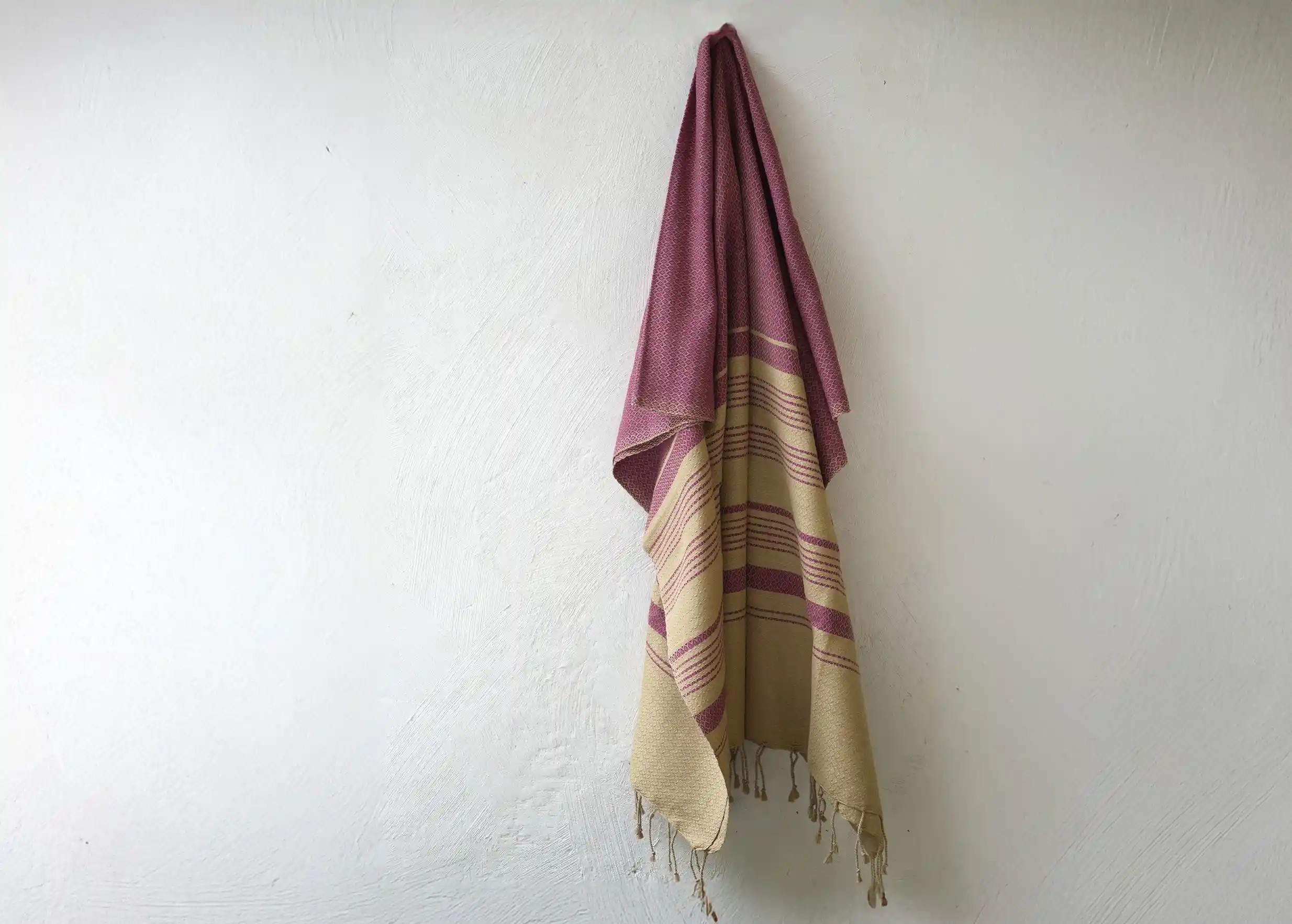 Fouta de la marque Karawan authentic en coton bio, suspendue contre un mur
