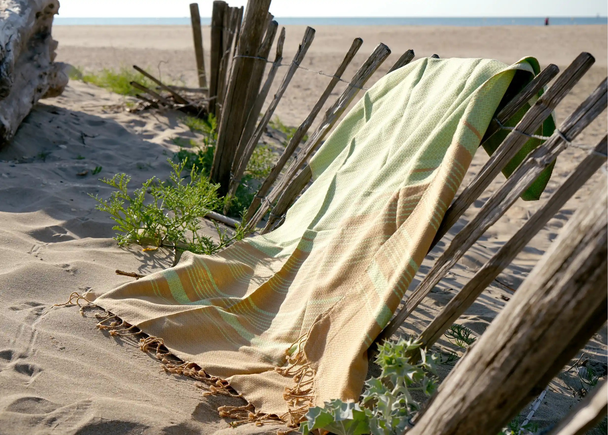 Pistachio-coloured fouta laid out like a path on the beach