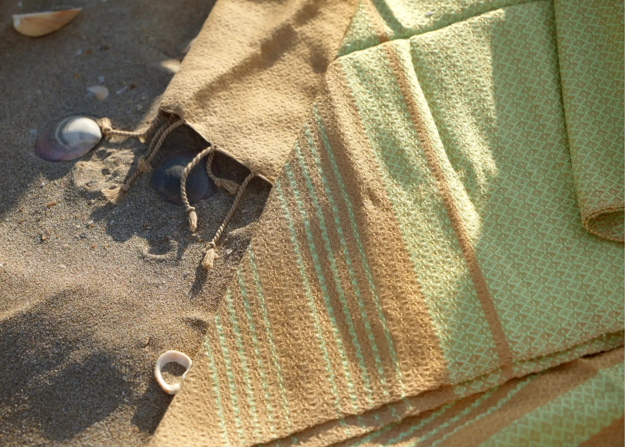 Focus on the details of the weave and fringes of the fouta in pine green, sand and shell colours.