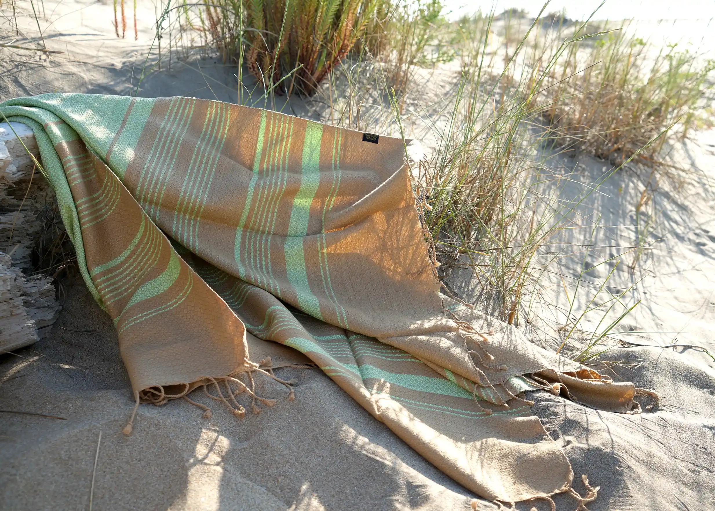 Fouta coloris pistache posee sur le sol de sable fin