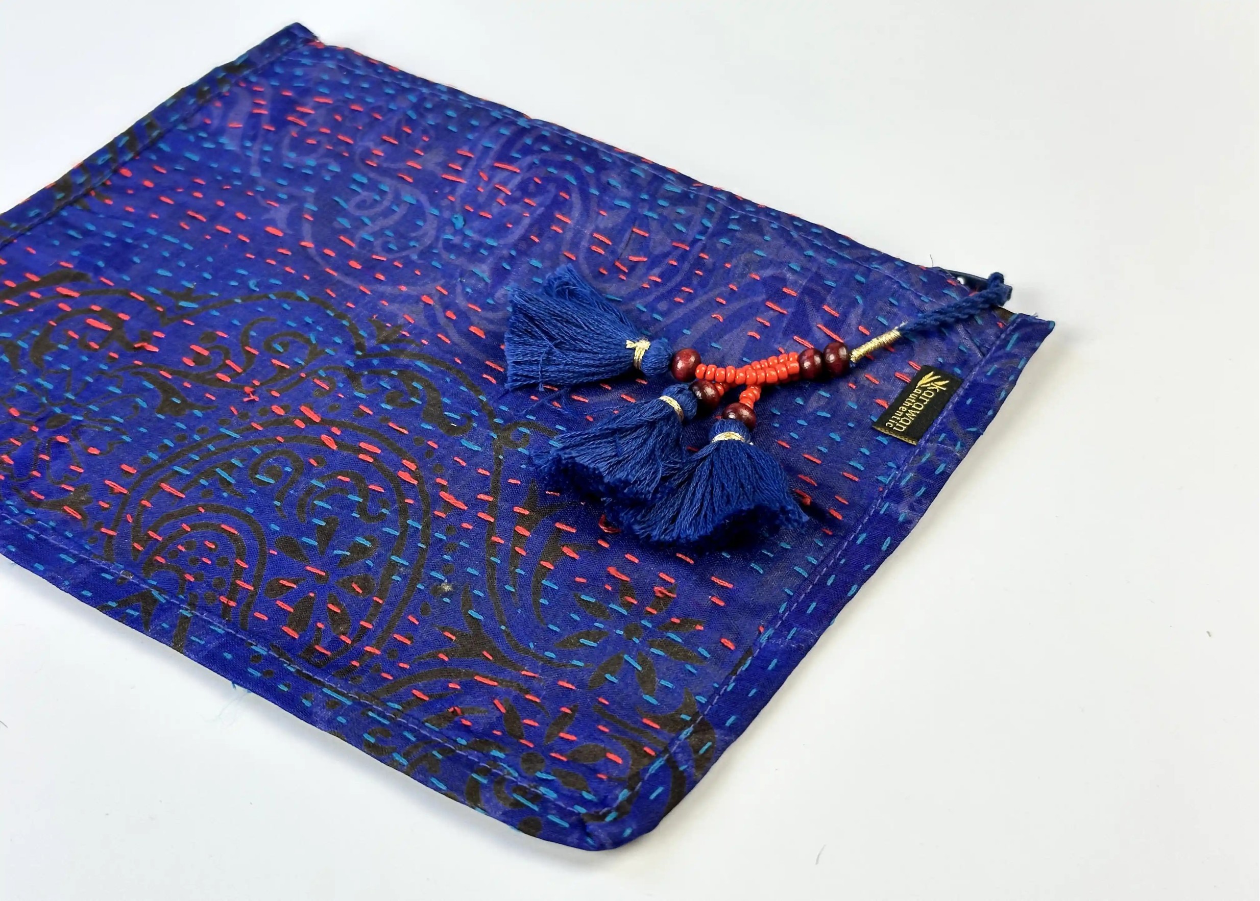 Zoom sur les details et le pompom de la pochette artisanale en soie kanta recyclée modèle n°06, photo prise sur fond blanc