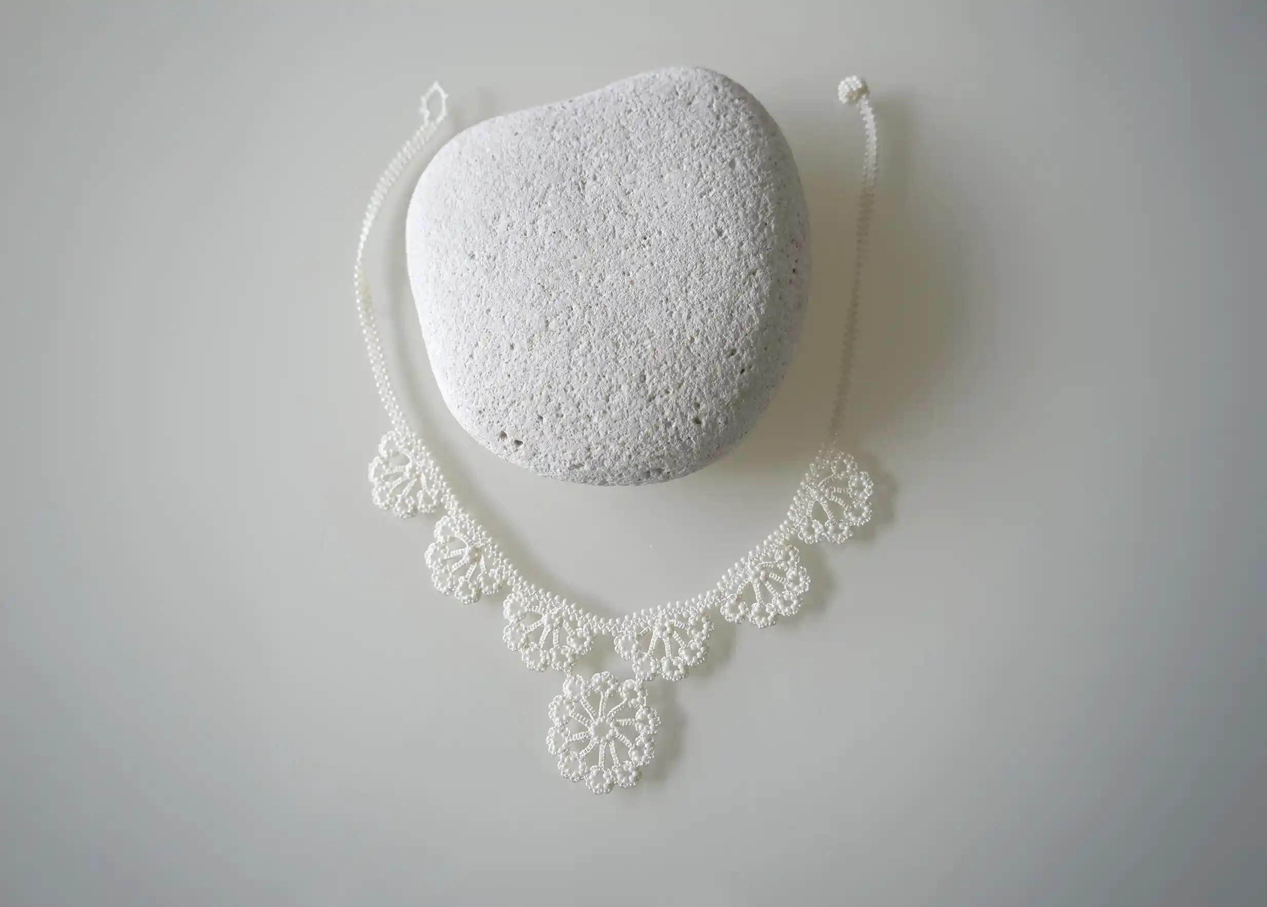 Motif floral en dentelle, orné de perles, sur un collier Hawa de couleur ivoire