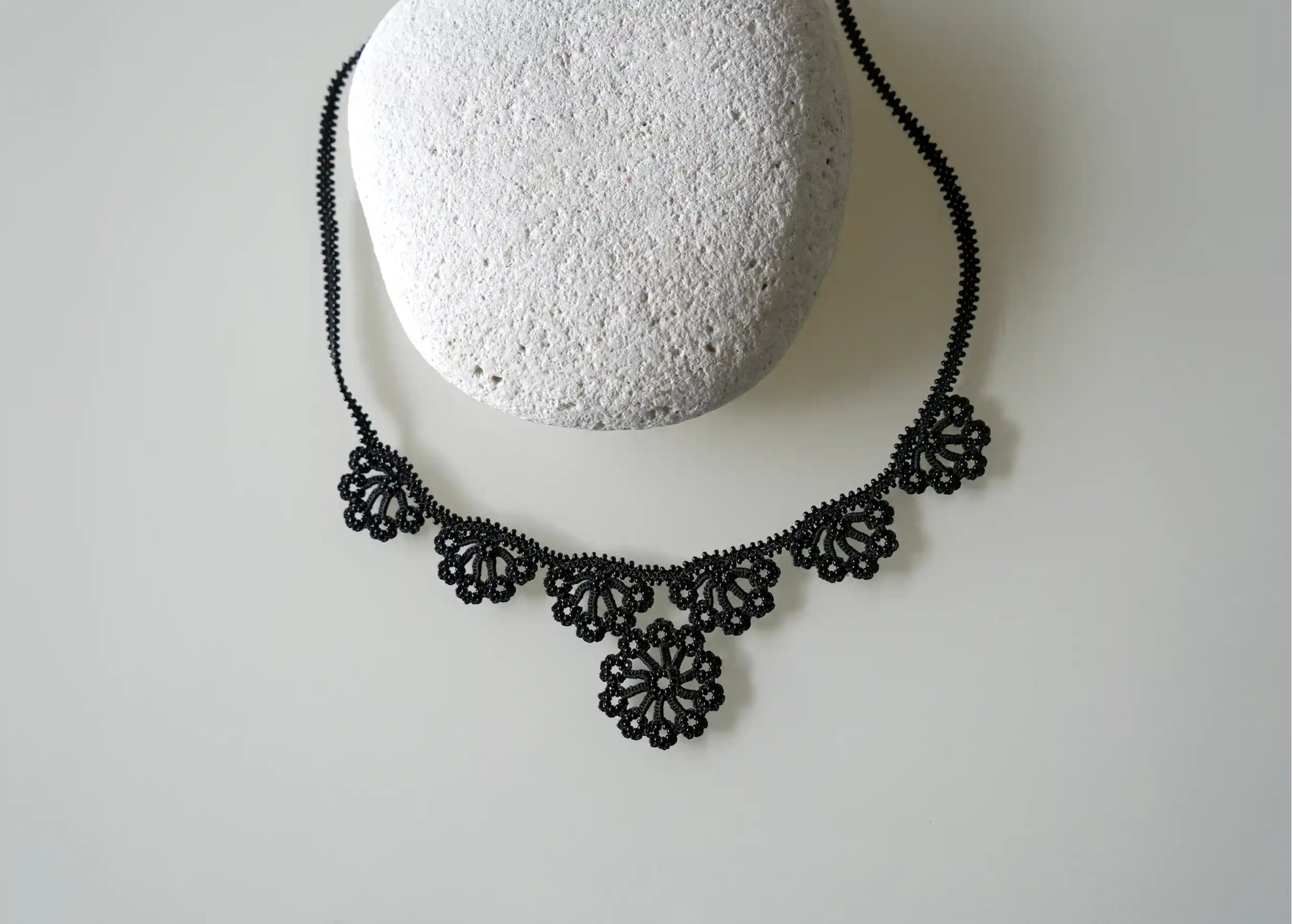 Motif floral en dentelle, orné de perles, sur un collier Hawa de couleur noire