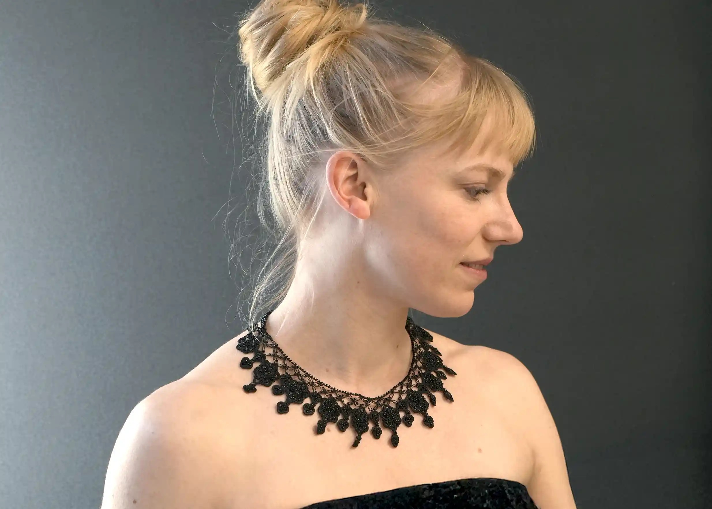 Femme portant un collier Sonya coloris noir  en dentelle Oya sur fond noir