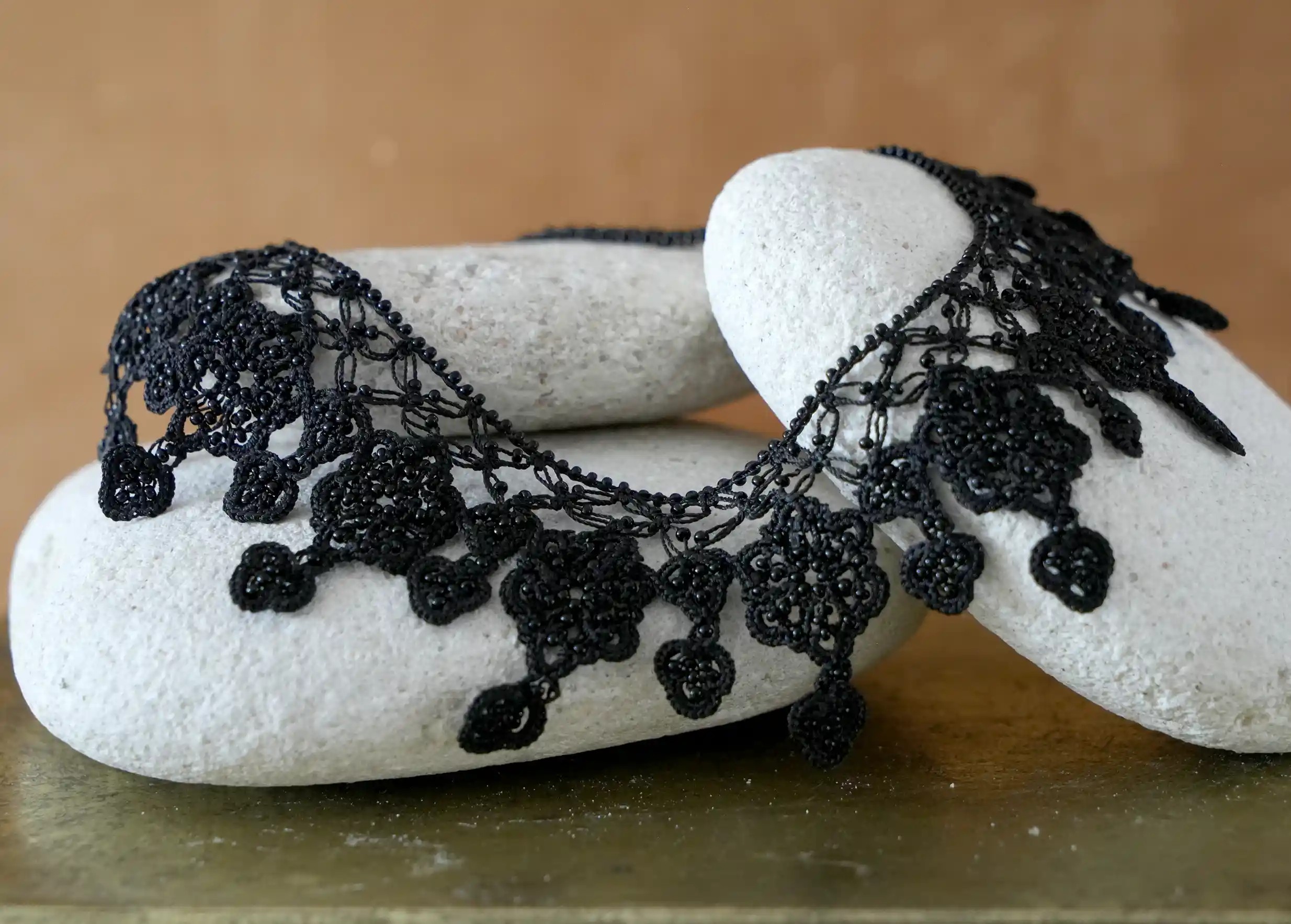 Focus on the motifs of the black Sonya necklace, hand-woven in lace