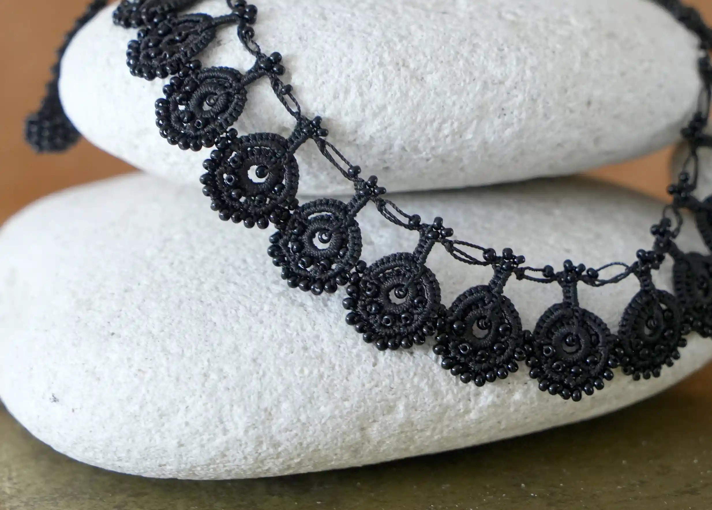 Zoom sur le collier en dentelle Eda noir carbone avec des motifs ornés de perles noires