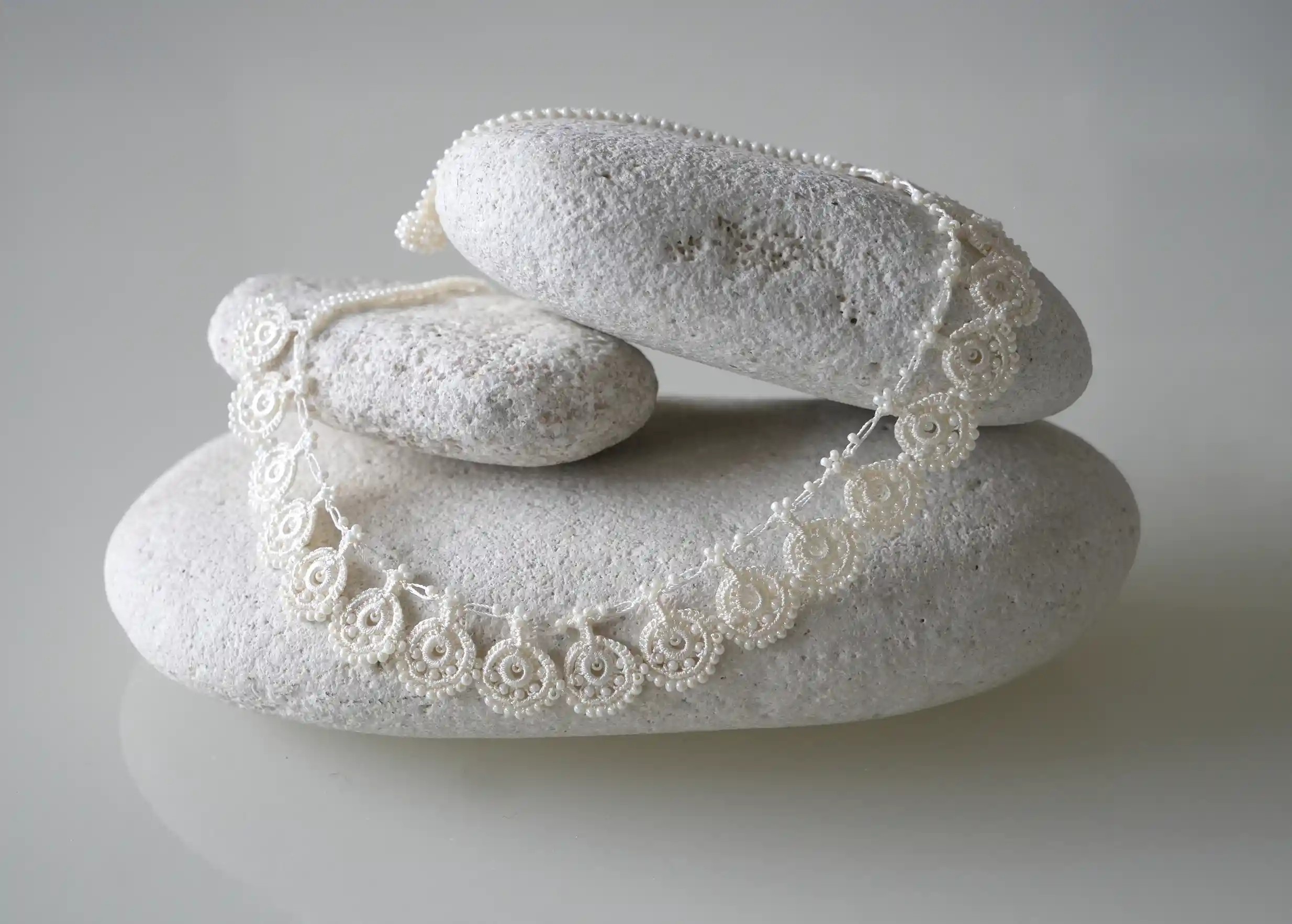 Collier en dentelle Eda coloris ivoire posé sur des galets gris