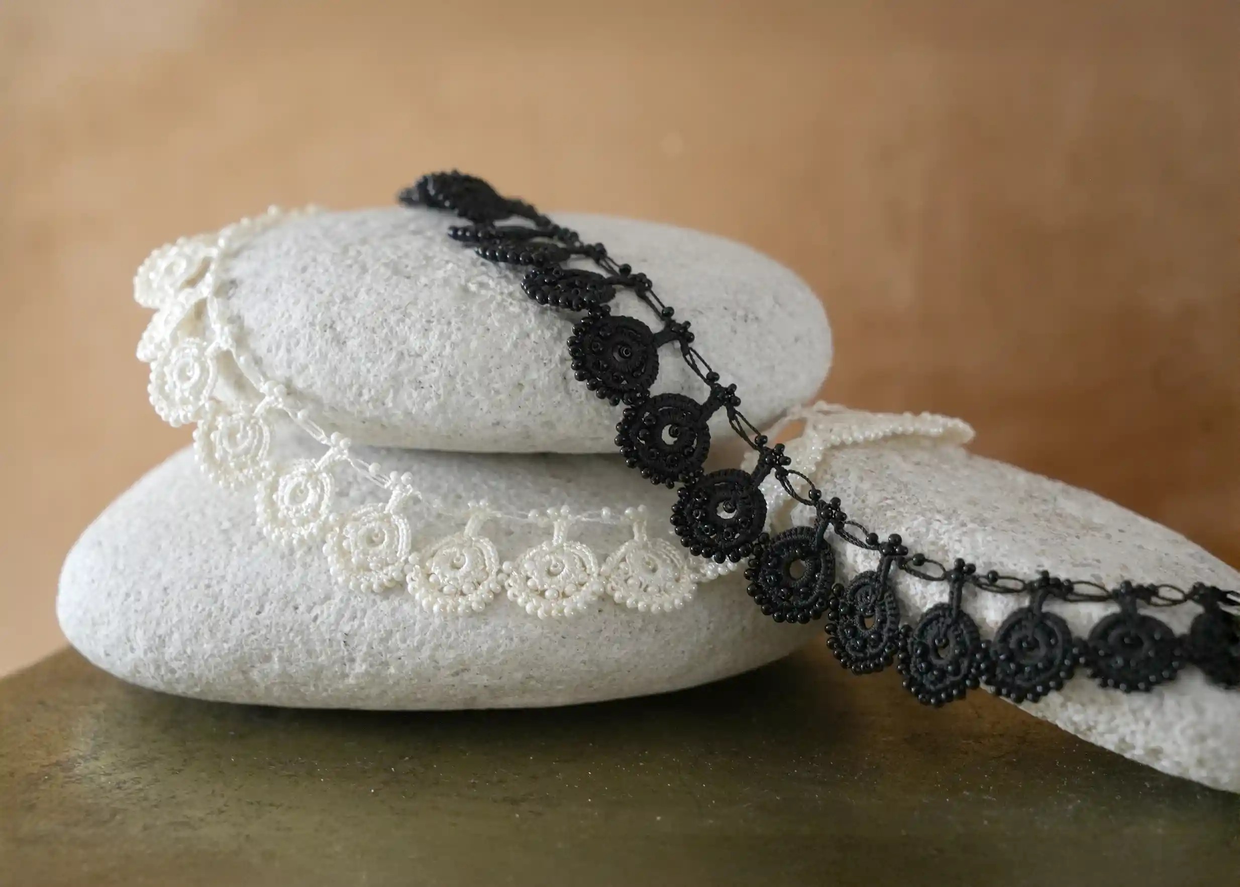 View of two colors of the Eda necklace by Karawan, in black and ivory lace