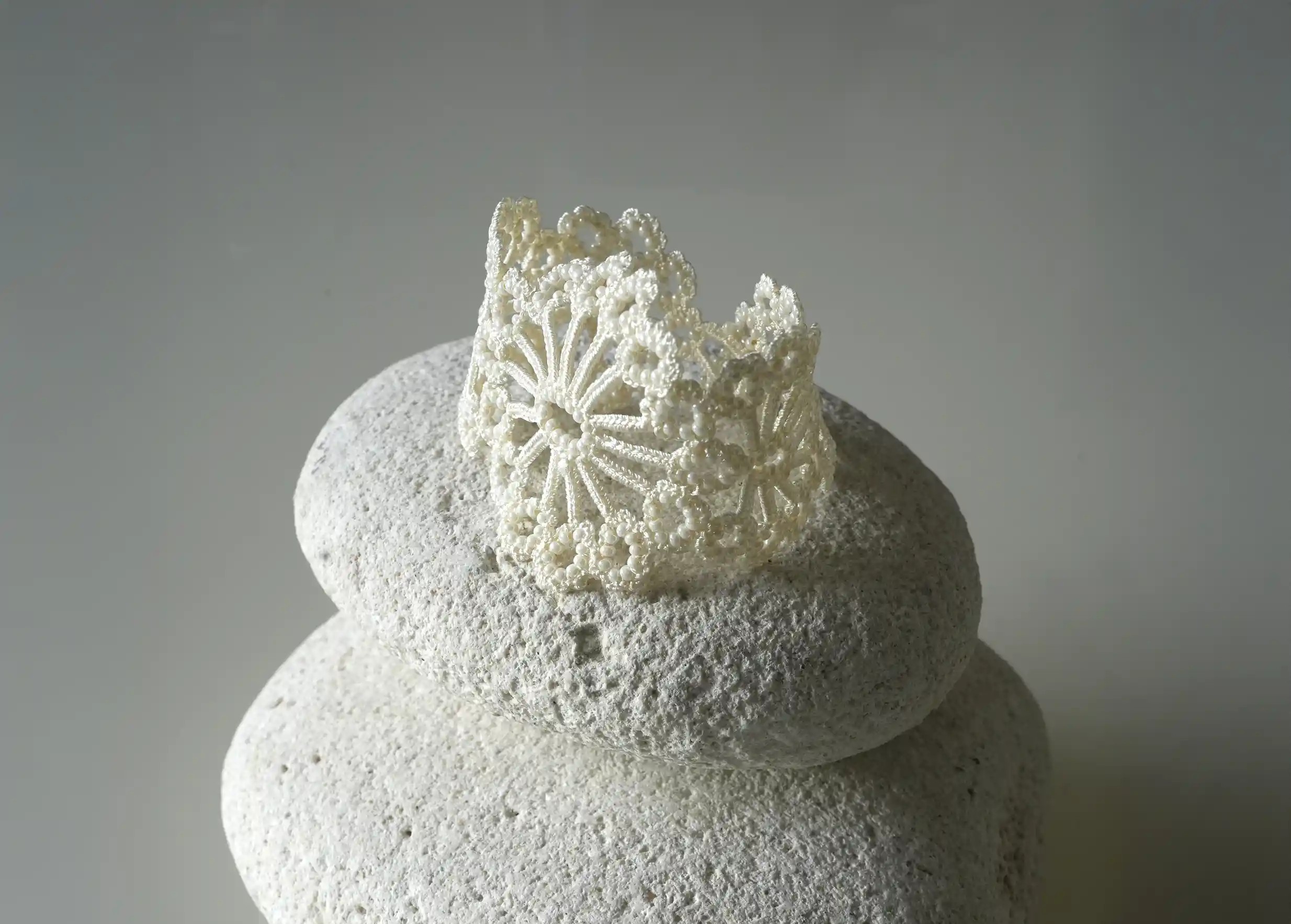 Close-up of the light ivory Hawa lace bracelet  placed on a white pebble