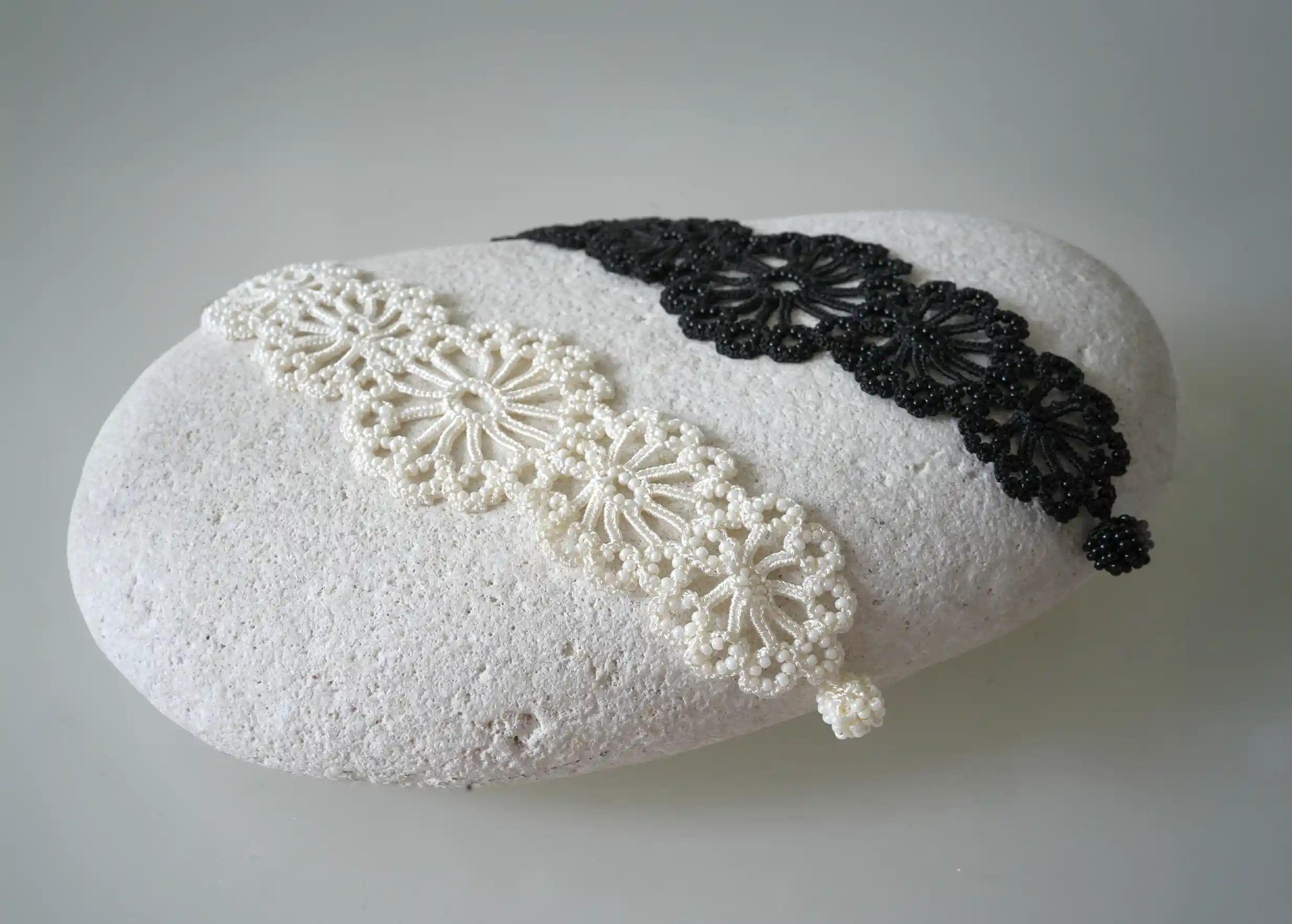 Two Turkish lace bracelets, black and ivory, placed on a pebble