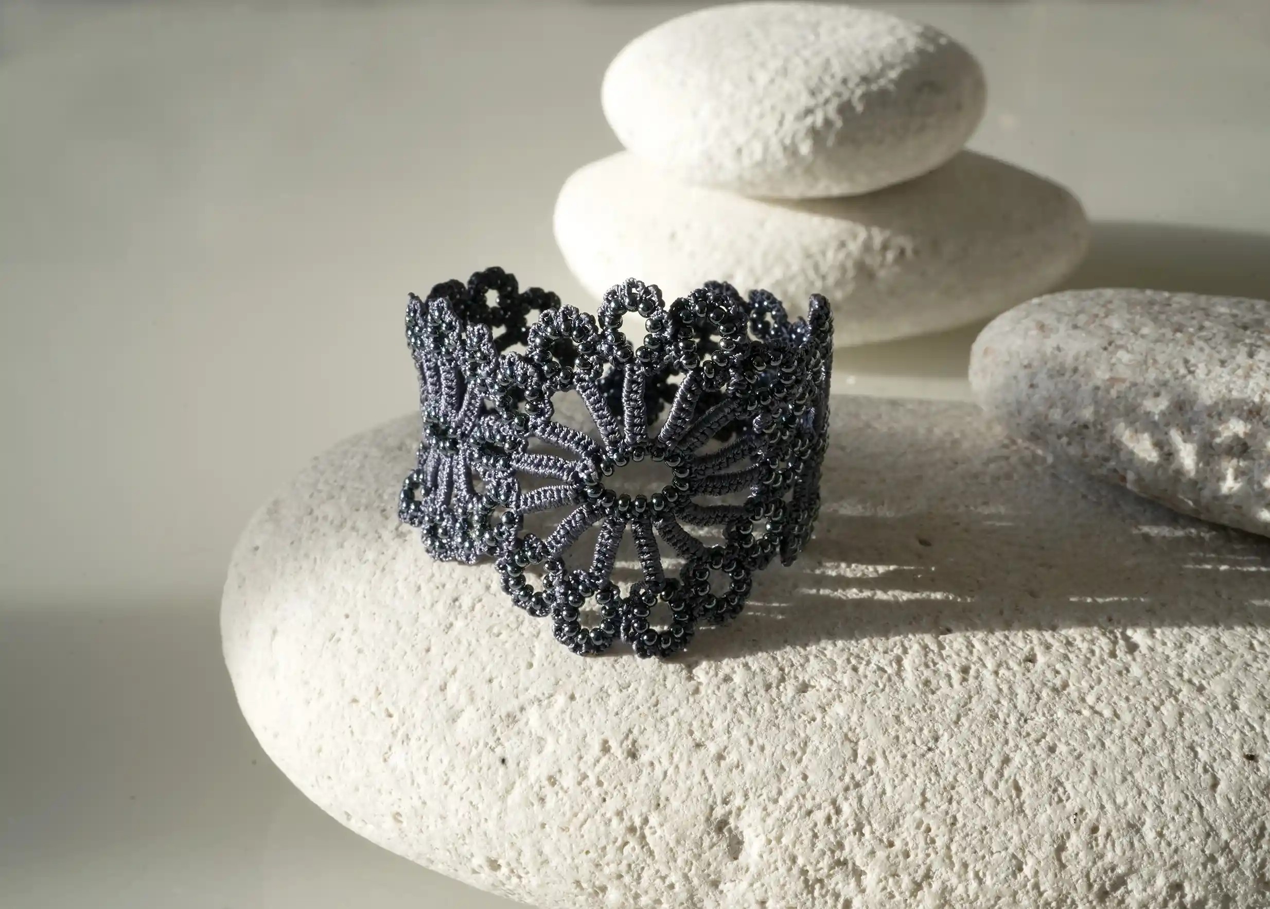 Close-up view of the slate bleue Hawa lace bracelet placed on a white pebble.